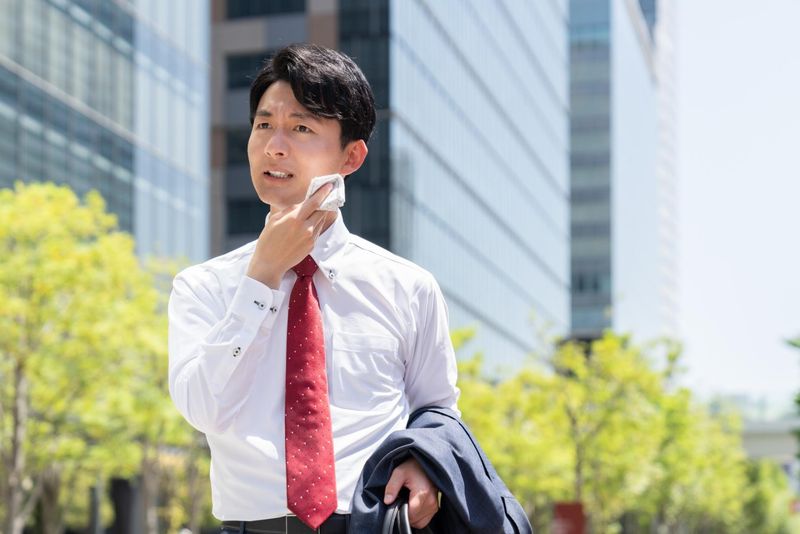 A businessman wiping sweat with a handkerchief