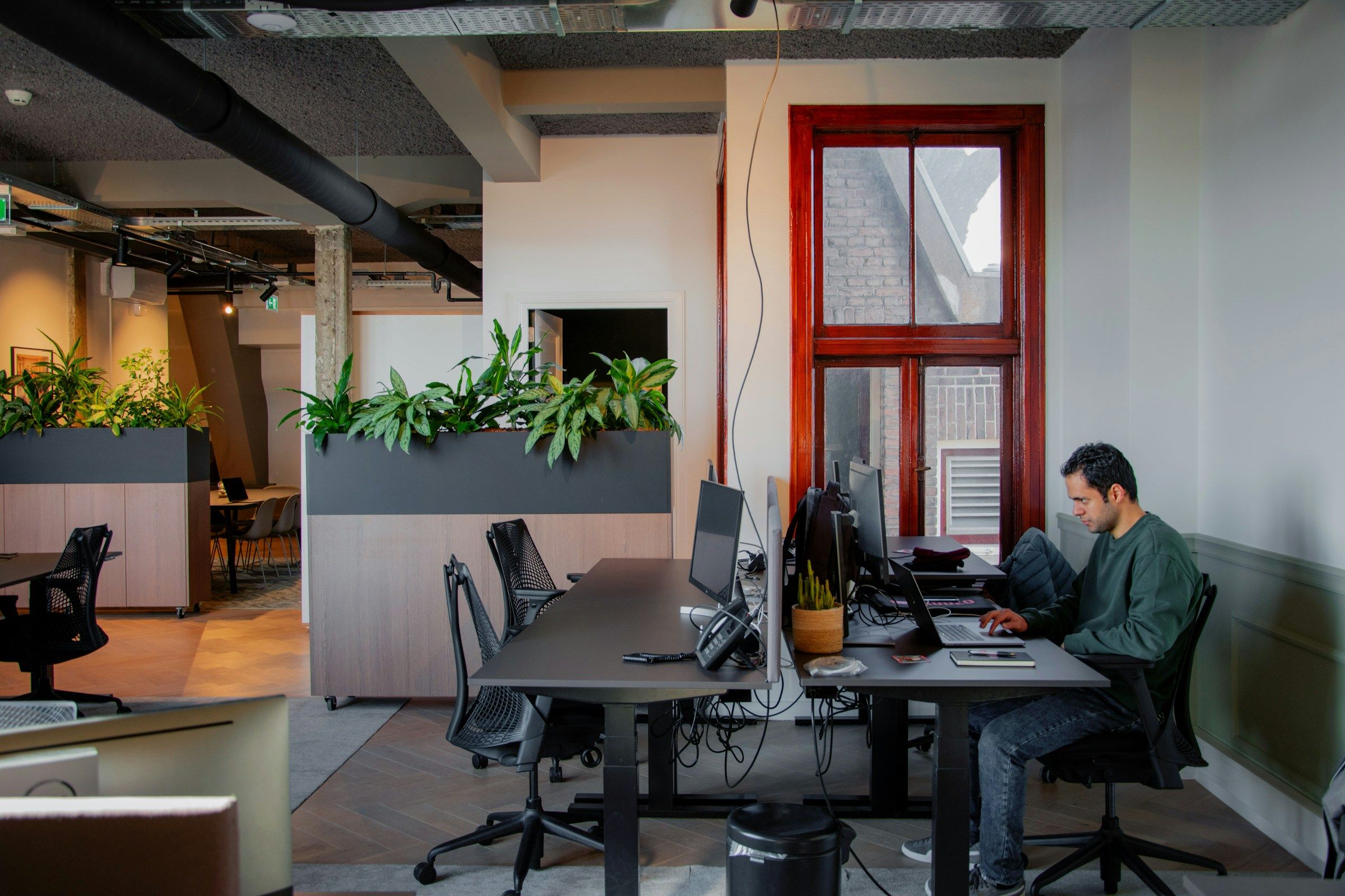 Lone colleague sat in an office studio at his computer desk.