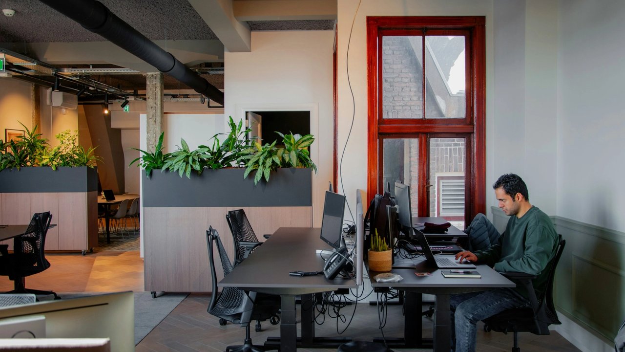 Lone colleague sat in an office studio at his computer desk.