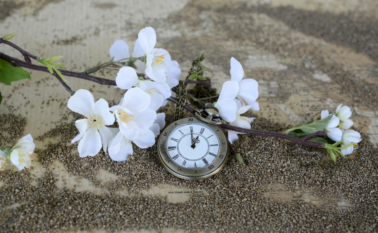 A clock with flowers around it. 