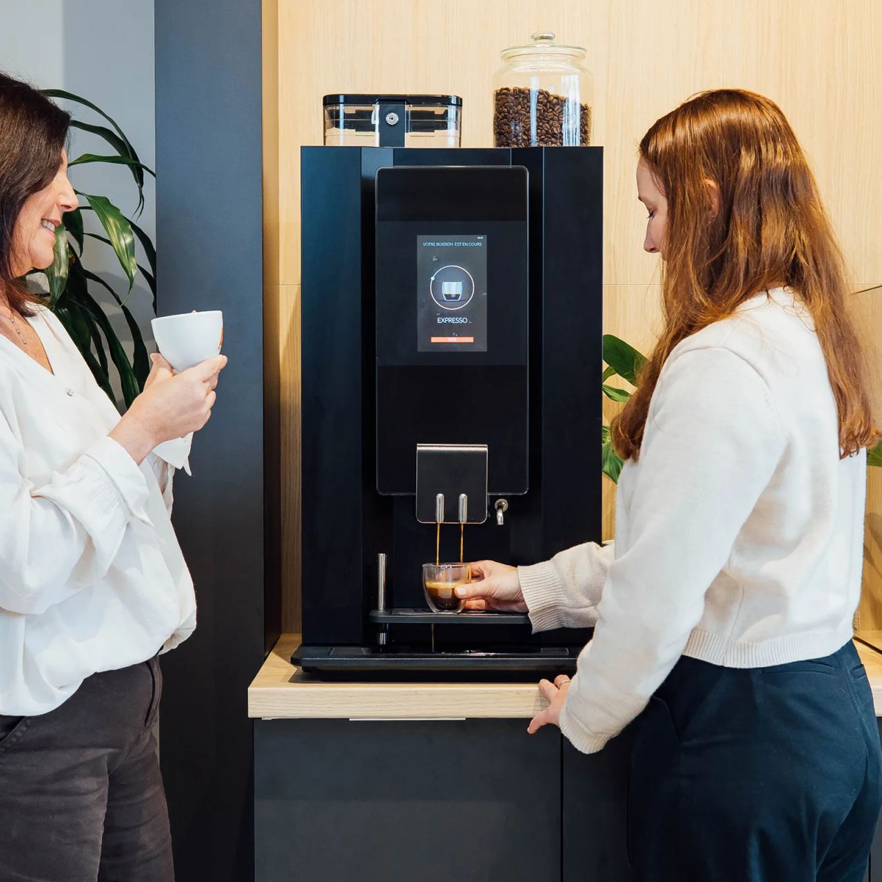 Deux collègues discutent autour de la machine à café