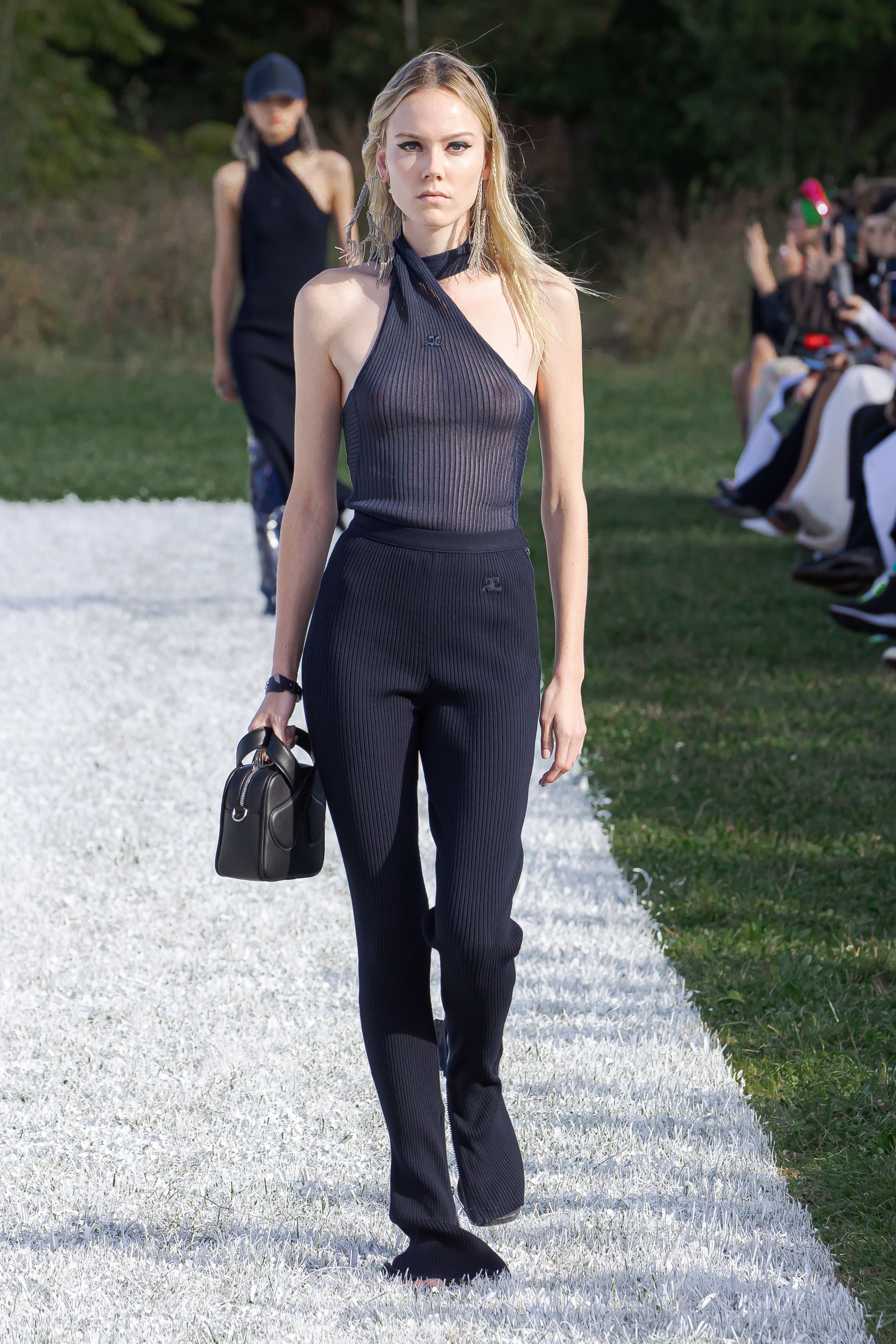 Elegant black ribbed sleeveless top and matching trousers on a model, Courrèges fashion showcase.