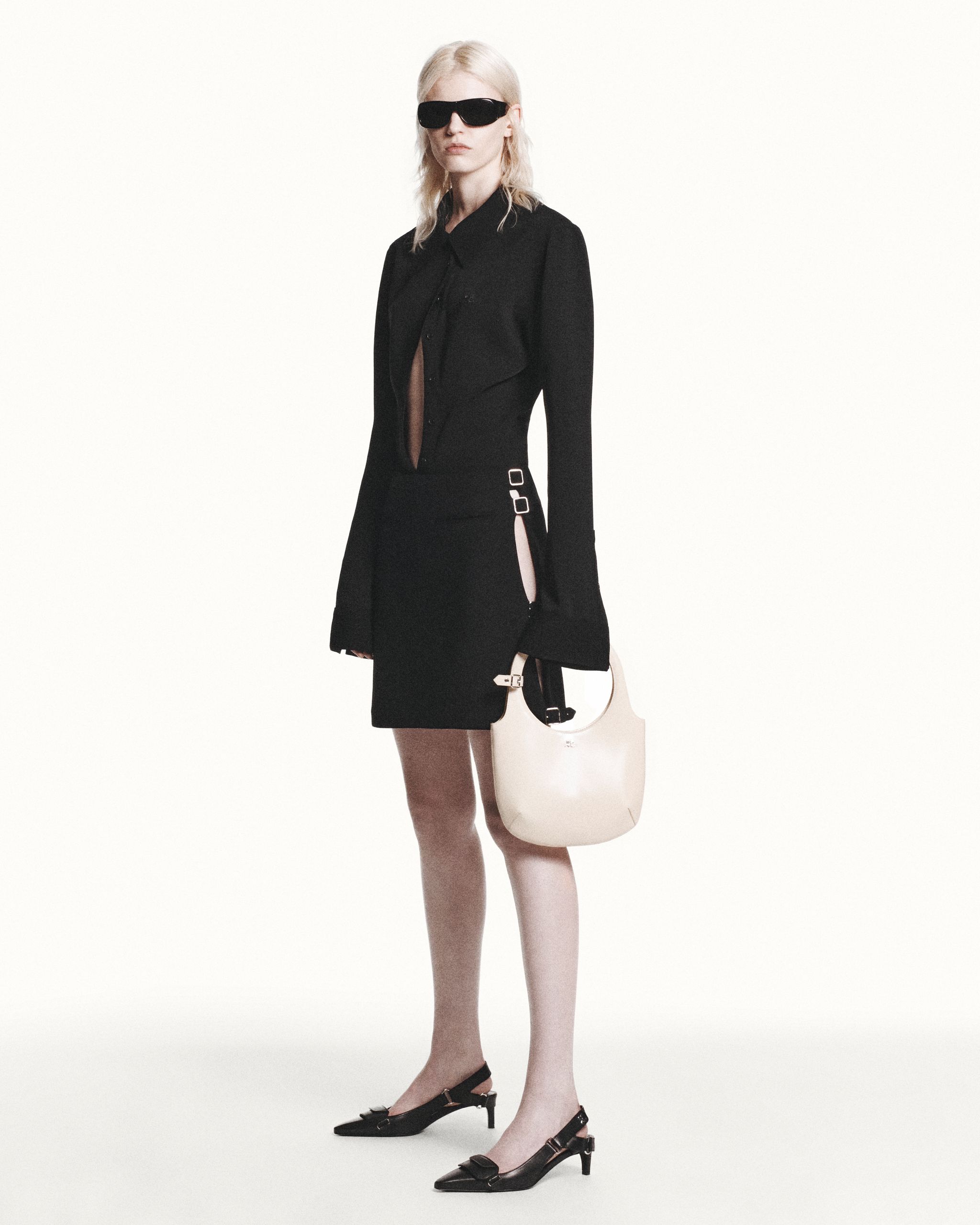 Elegant black avant-garde dress by Courrèges featuring cut-outs, buckle accents, and chic accessories.