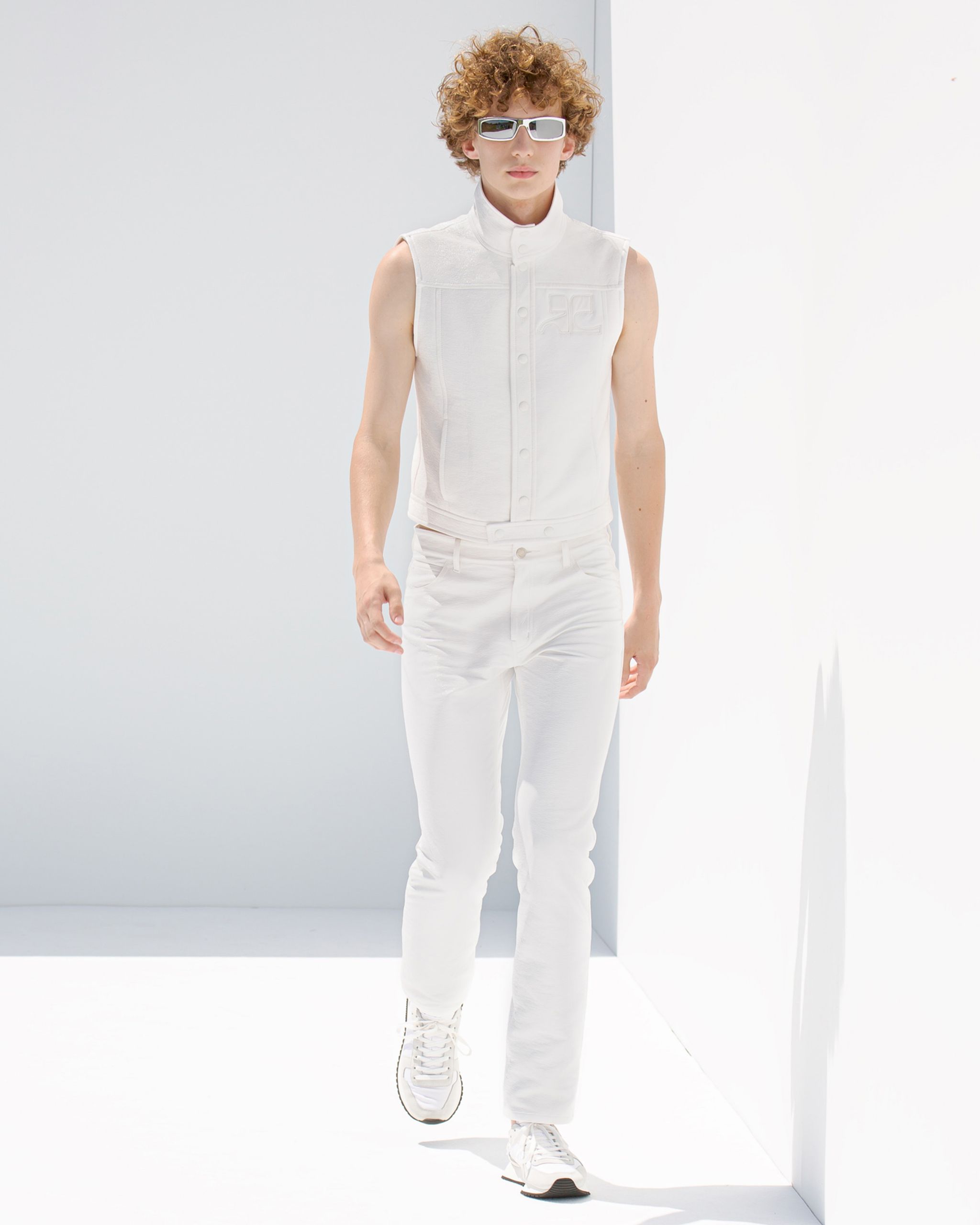 Model in all-white futuristic Courrèges fashion outfit with sunglasses for an ecommerce site.