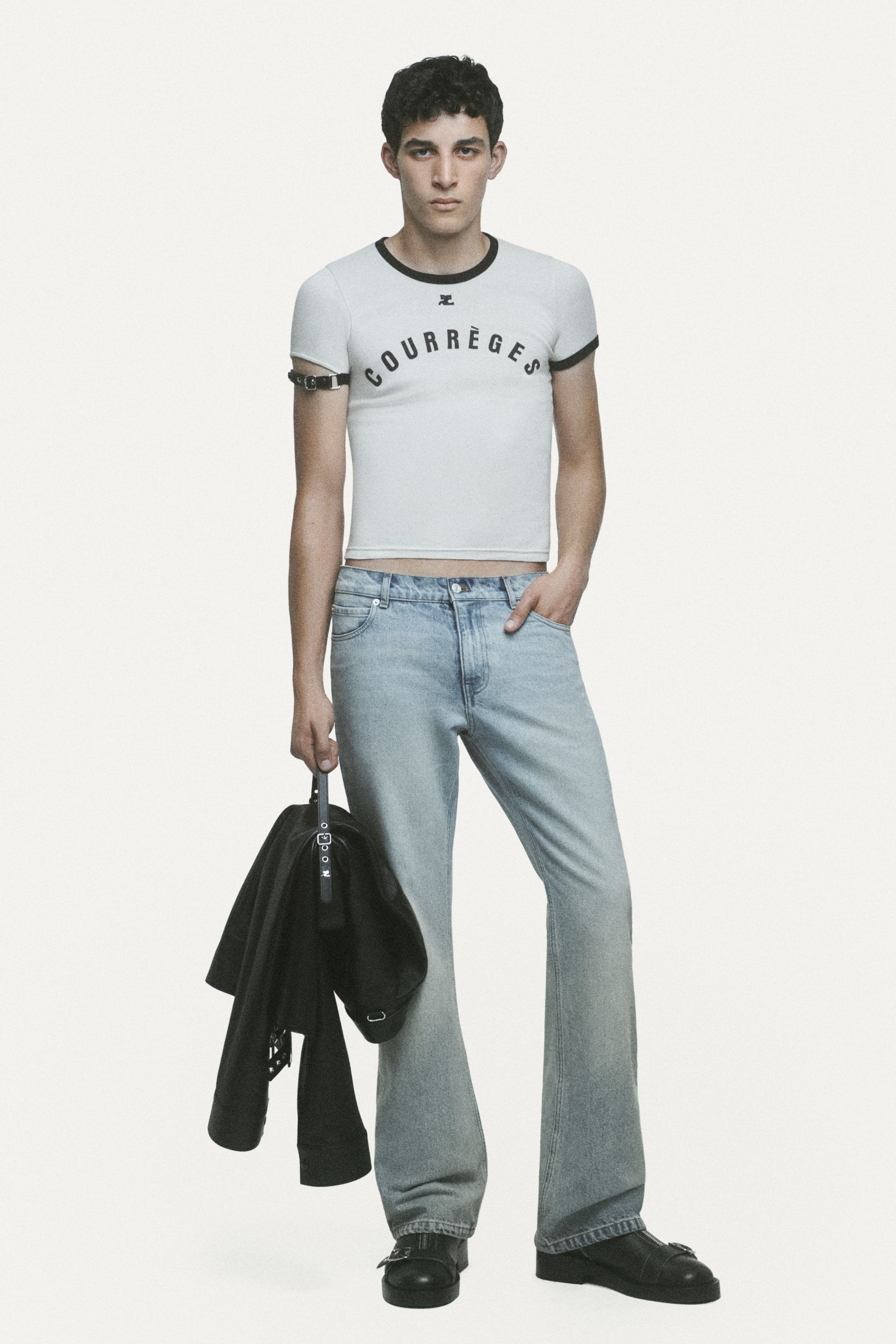 Stylish male model wearing Courrèges casual white crop top and light jeans for modern fashion.