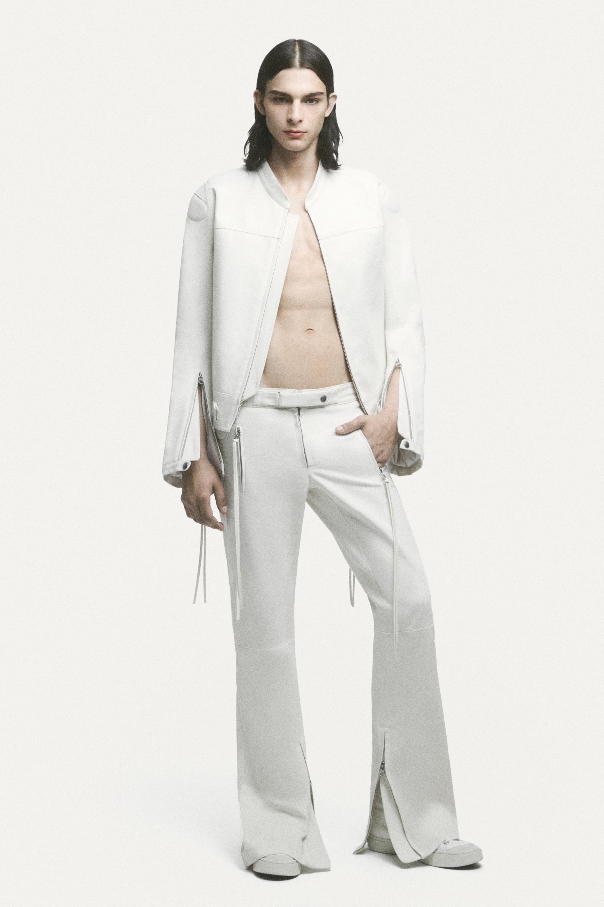 Elegant male model in white Courrèges fashion, showcasing contemporary minimalist style.