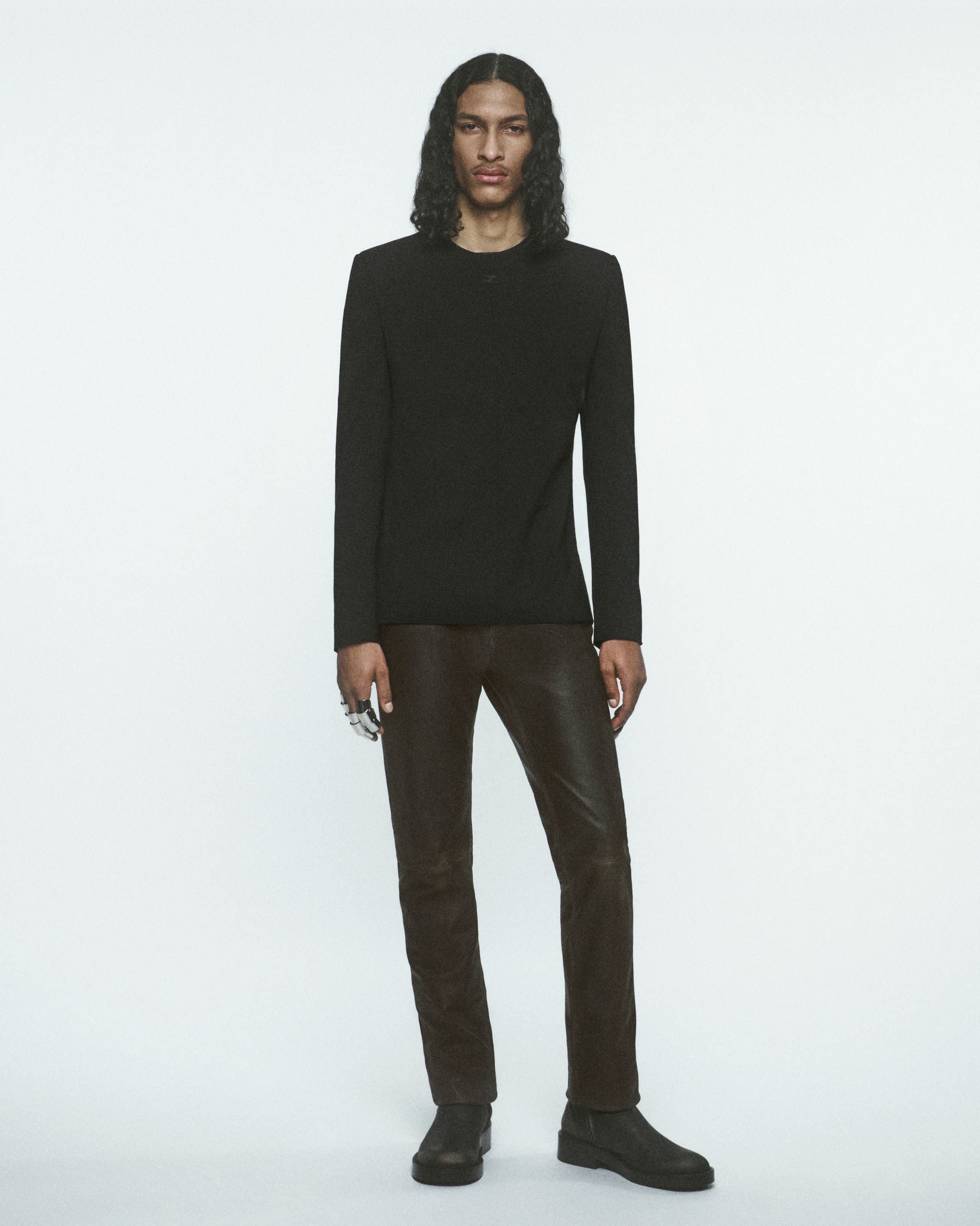 Pull noir élégant et pantalon en cuir présentent la mode Courrèges sur un modèle minimaliste.