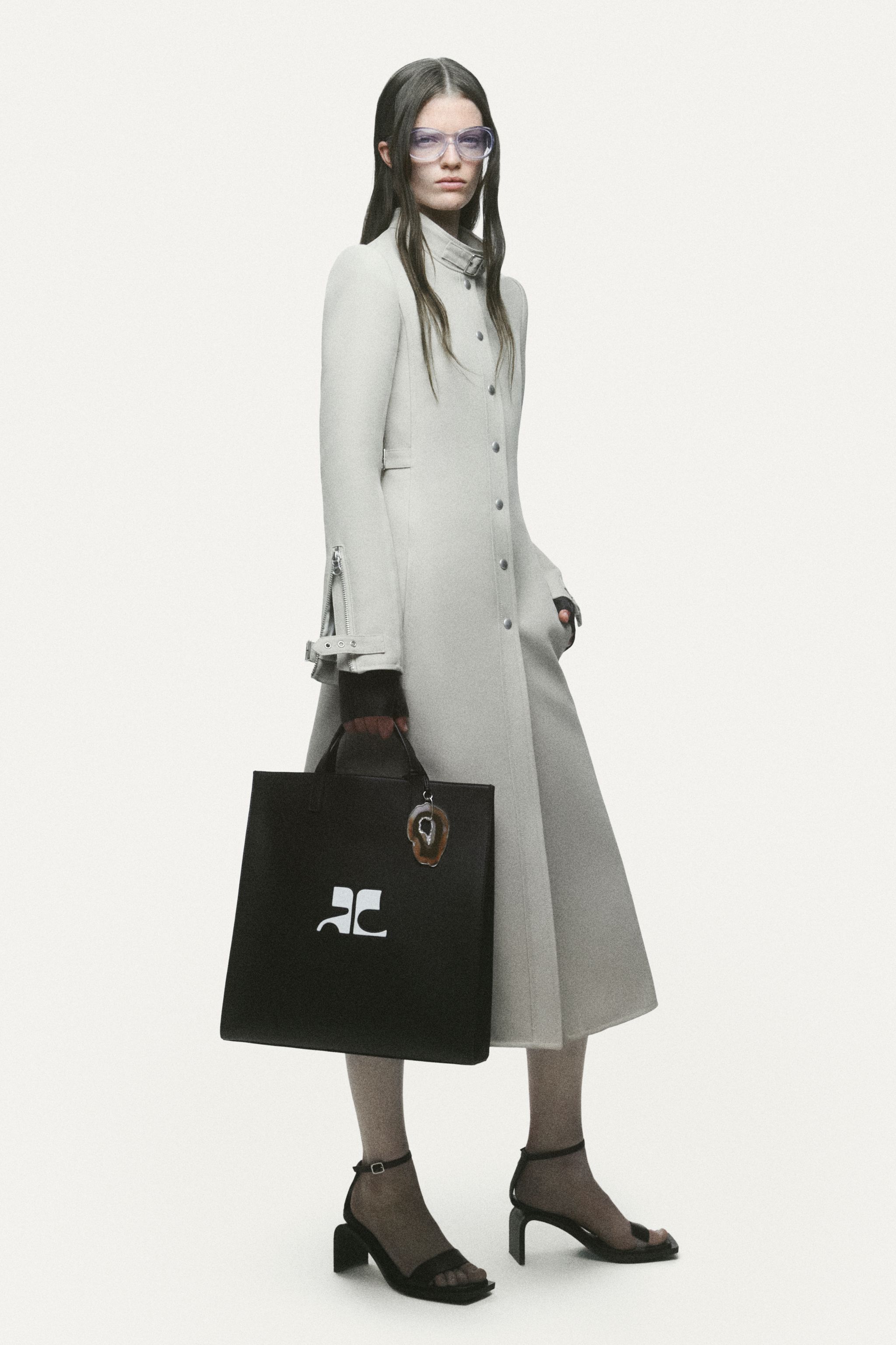 Elegant black dress with zipper details, stylishly paired with thigh-high boots and sunglasses for Courrèges.