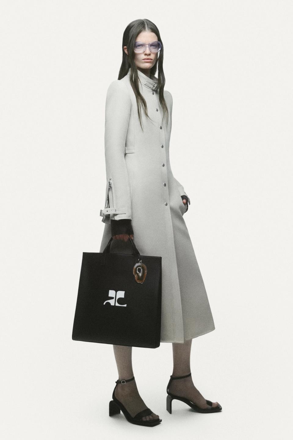 Elegant black dress with zipper details, stylishly paired with thigh-high boots and sunglasses for Courrèges.