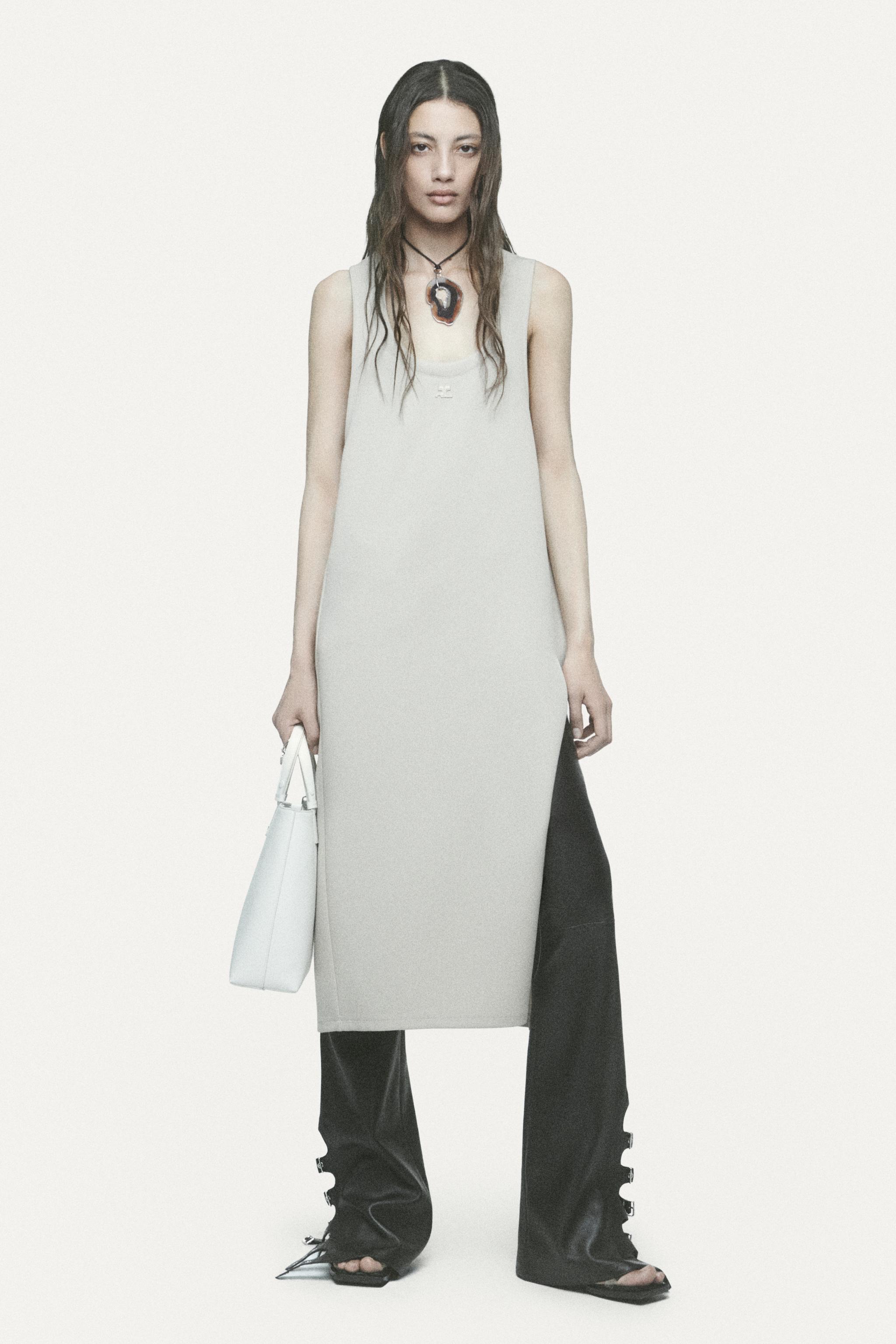 Elegant model wearing Courrèges minimalist dress with black wide-leg pants on ecommerce site.