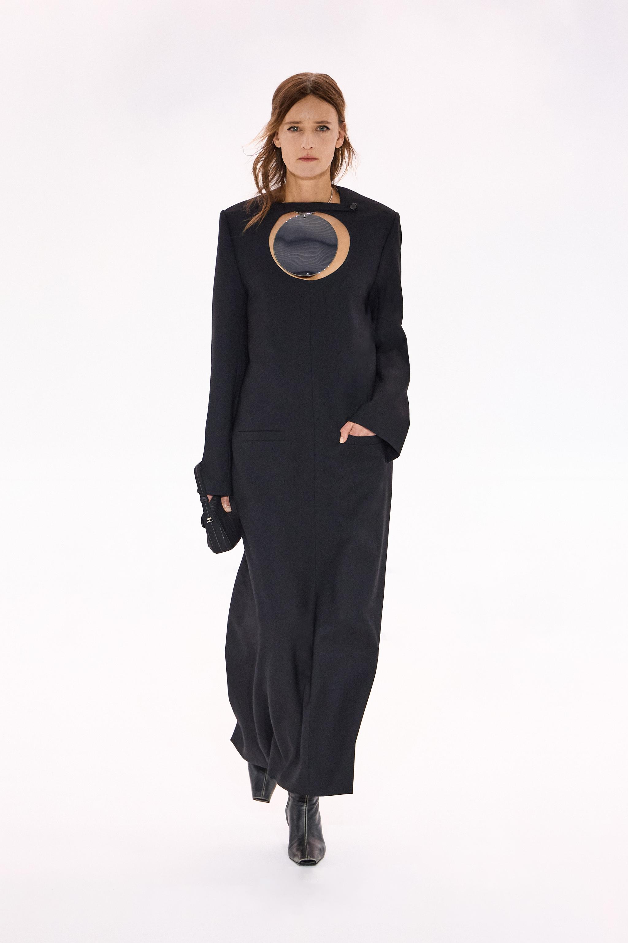 Elegant black dress with modern cutouts, showcasing Courrèges fashion on a runway.