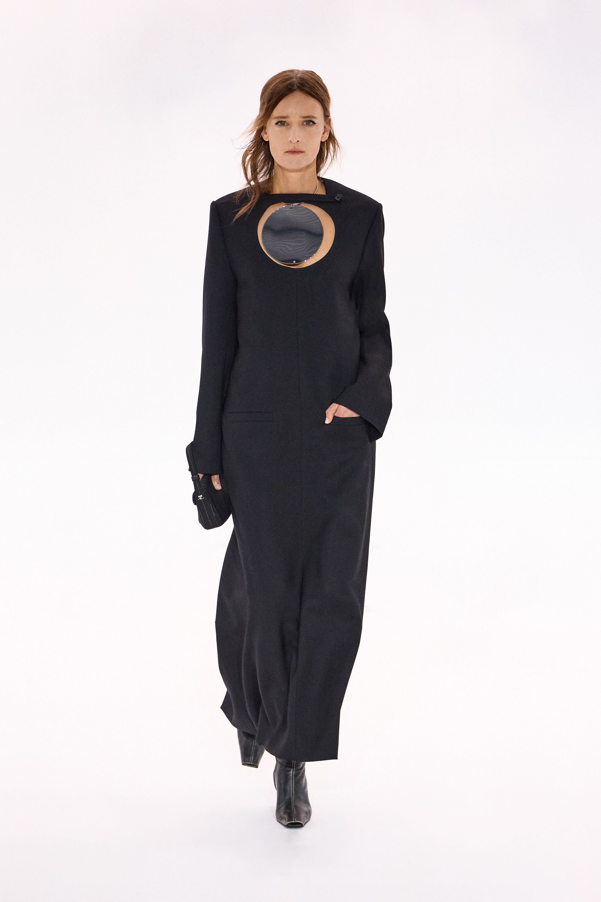 Elegant black leather dress featuring a mirror cutout, showcased on a fashion runway for Courrèges.