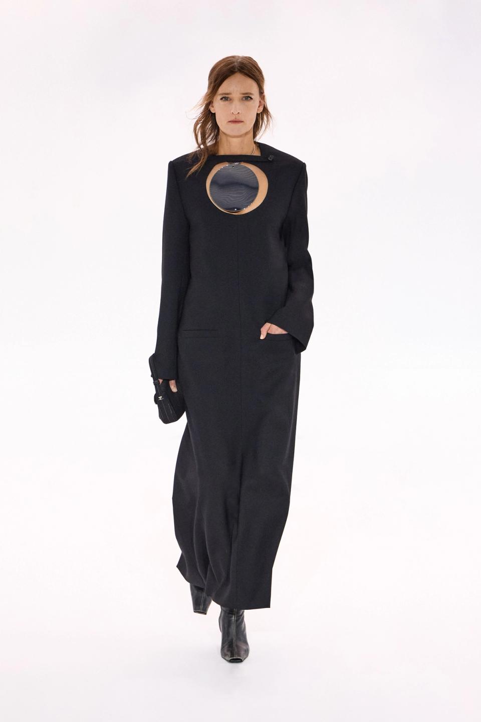 Elegant black leather dress featuring a mirror cutout, showcased on a fashion runway for Courrèges.