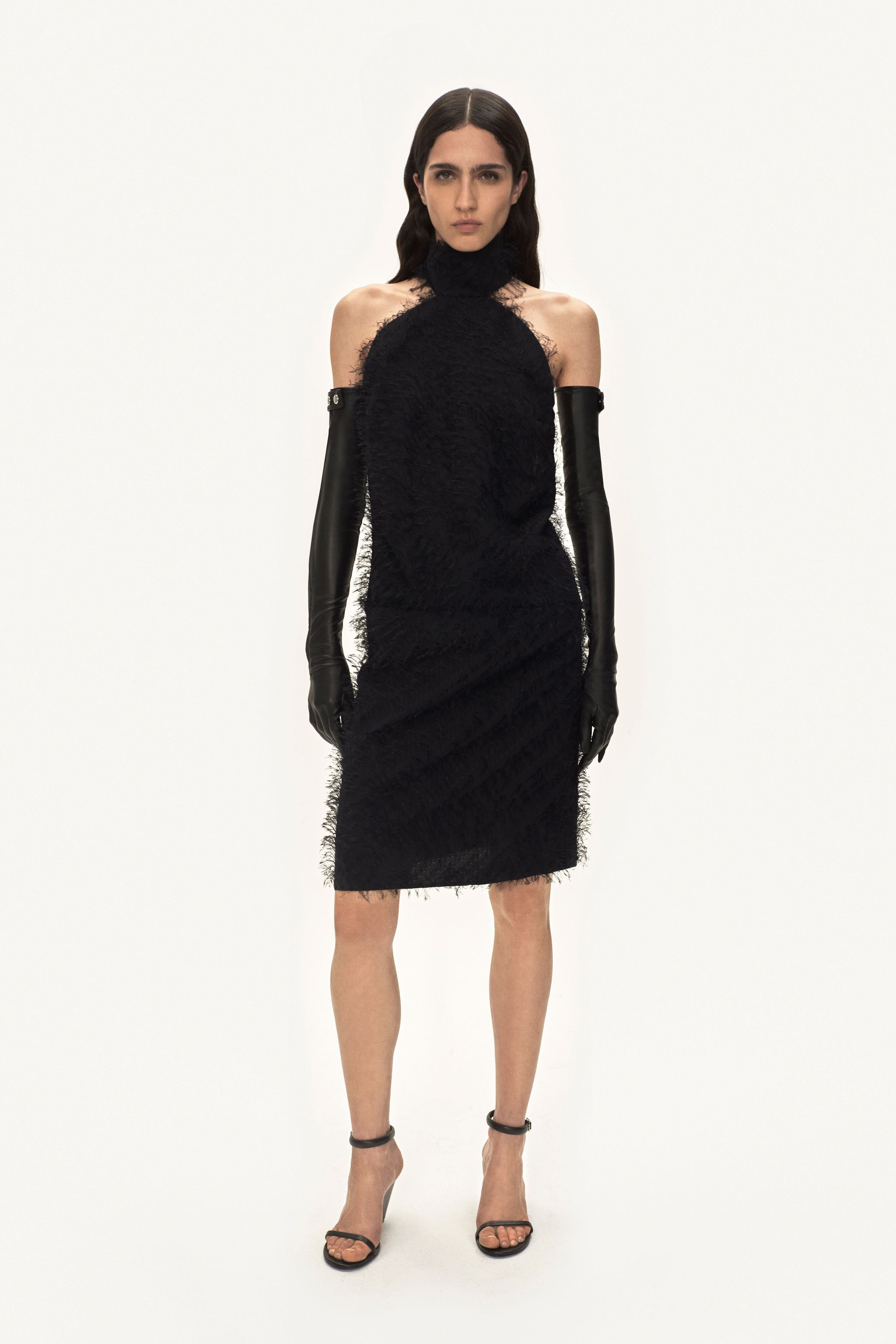 Elegant black dress by Courrèges with textured fabric, paired with long leather gloves and heels.