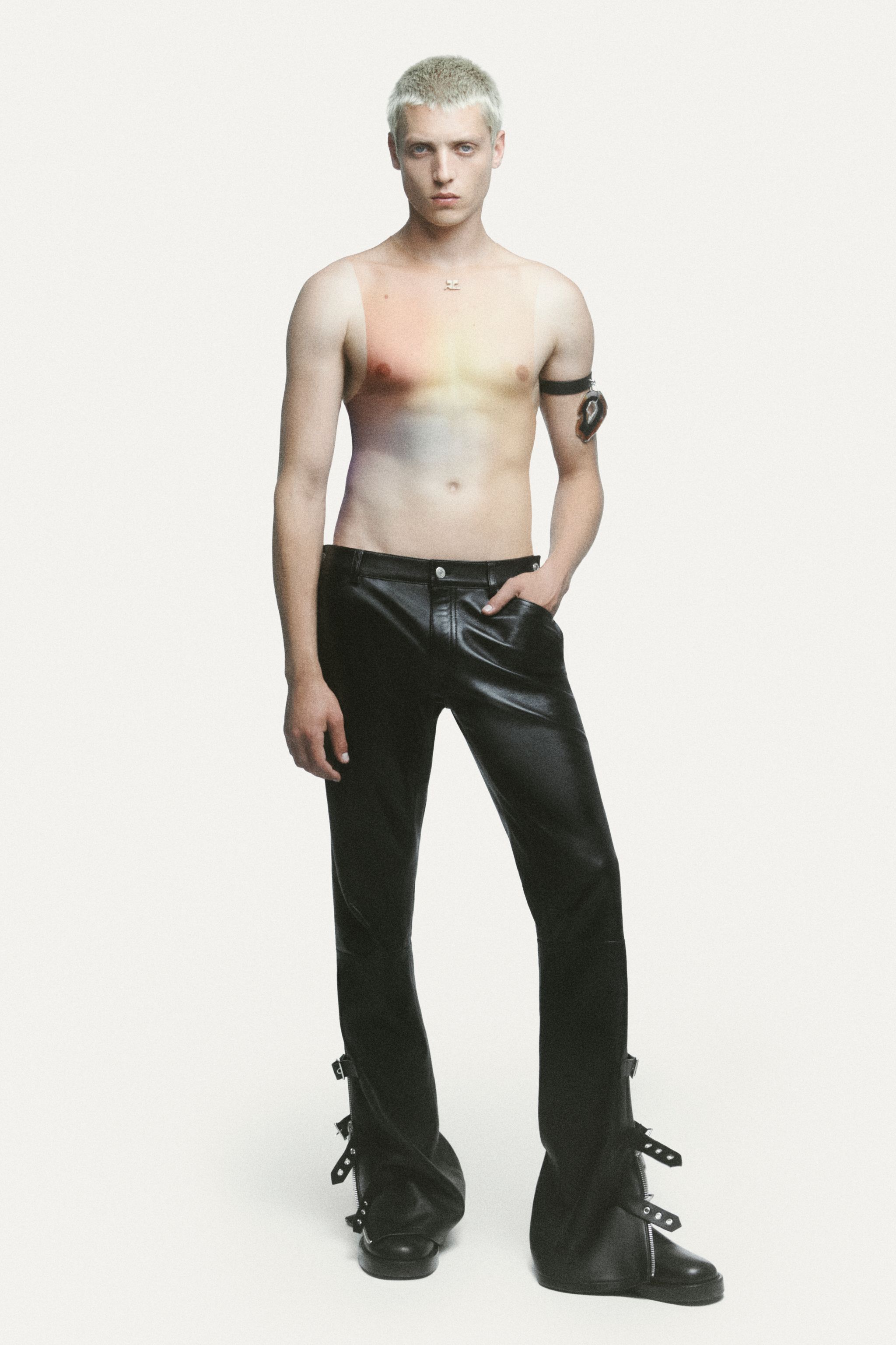 Male model with platinum blonde hair wearing leather pants and a futuristic body art design, Courrèges fashion.