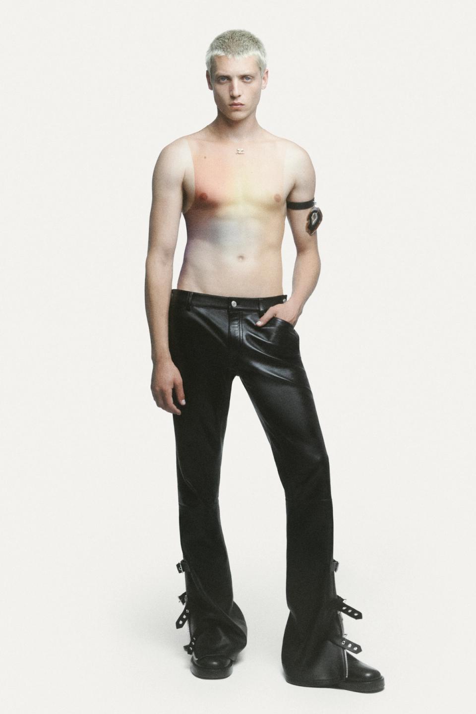 Male model with platinum blonde hair wearing leather pants and a futuristic body art design, Courrèges fashion.
