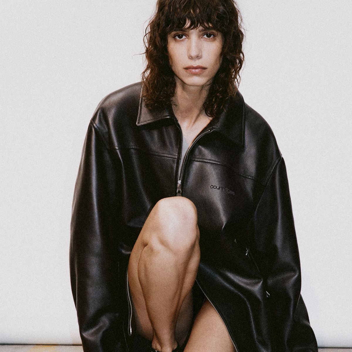Elegant black leather Courrèges jacket showcased in a modern fashion ecommerce setting.