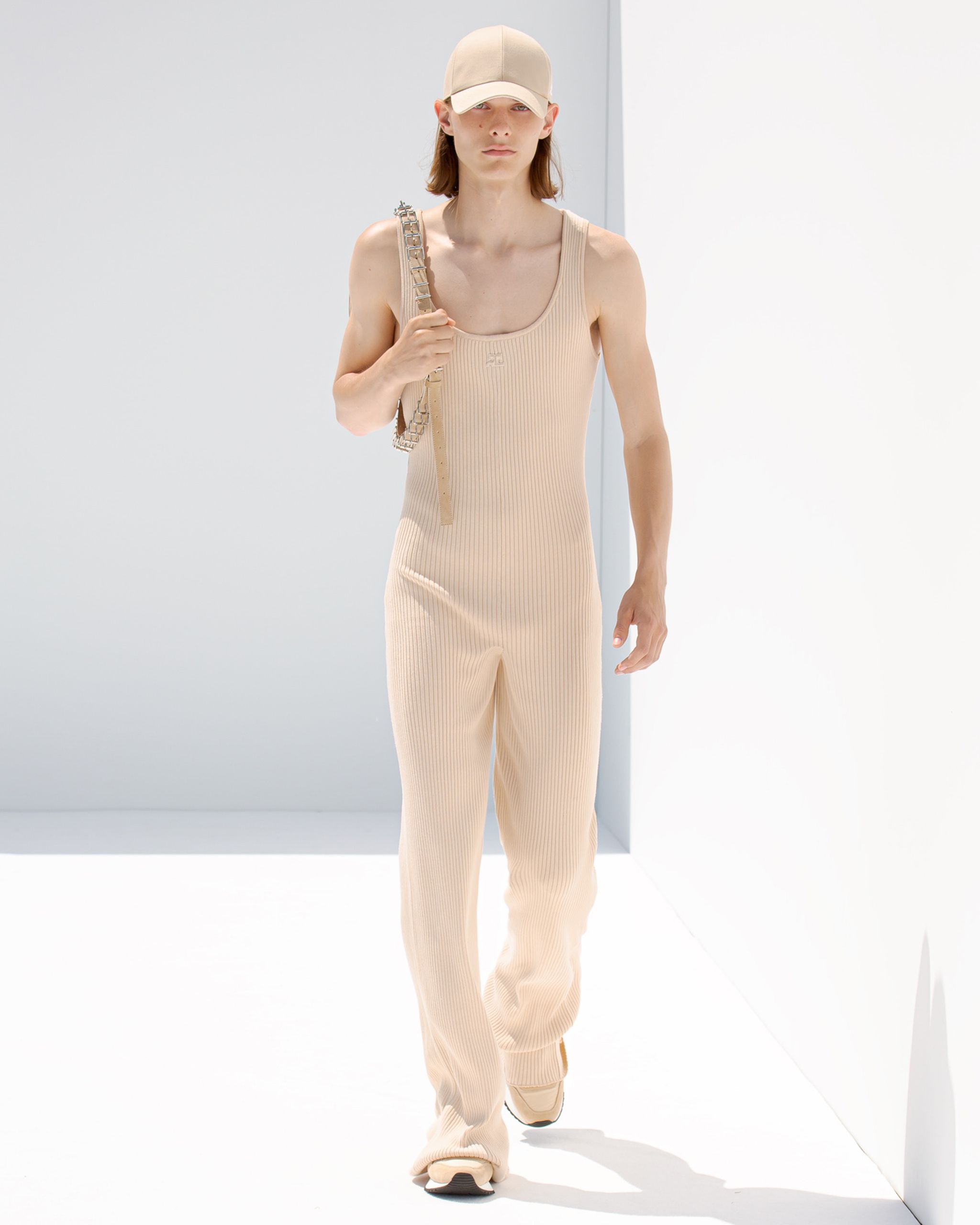 Elegant beige ribbed jumpsuit with casual accessories, showcased by Courrèges for fashion lovers.
