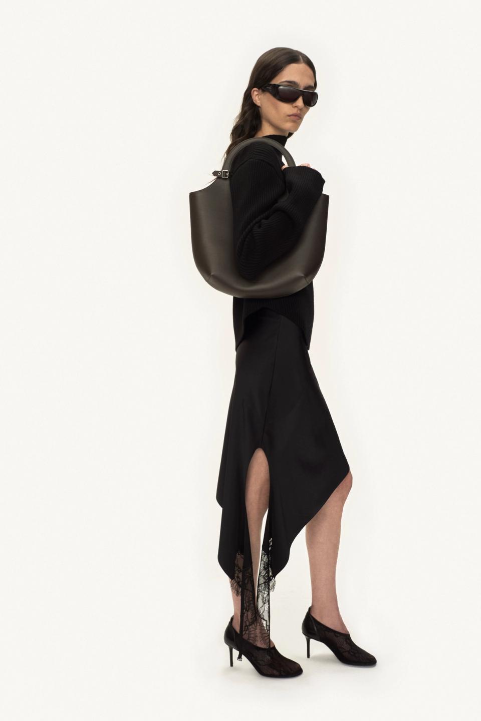 Elegant black outfit with lace shoes and a large bag, showcasing Courrèges fashion.