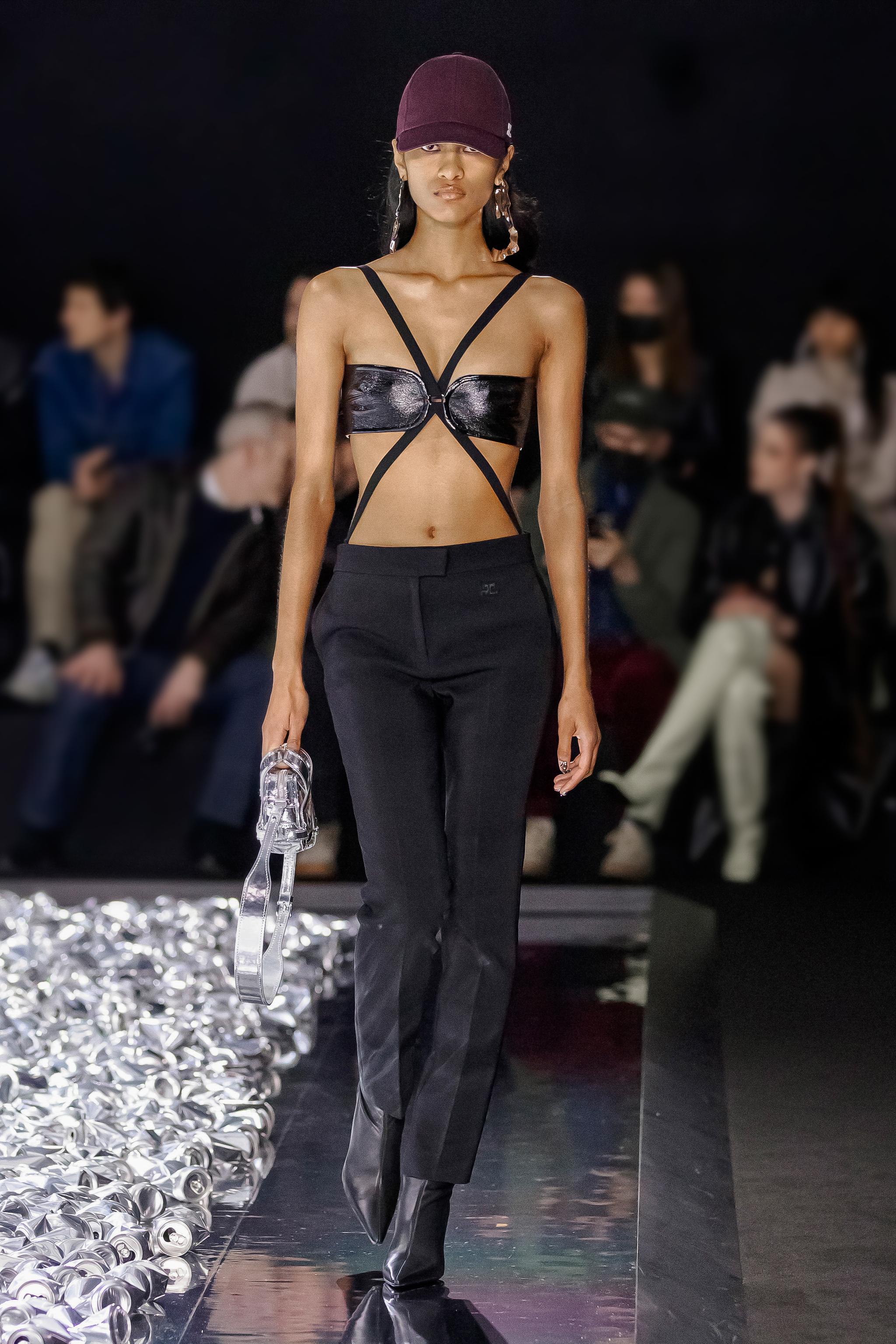 Elegant model in black fashion, showcasing Courrèges clothing on runway for ecommerce site.