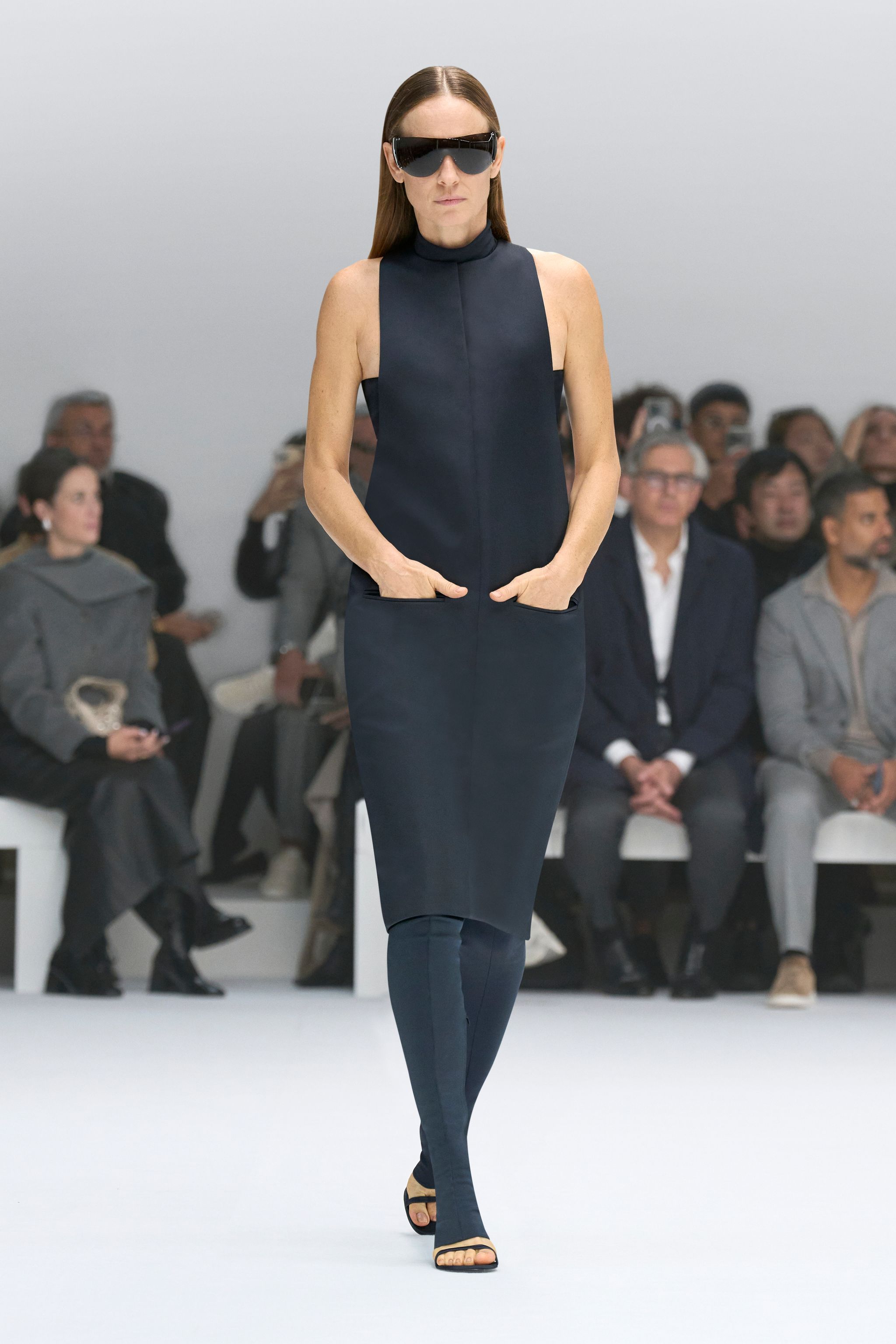 Elegant black sleeveless dress with high neck, showcased by Courrèges on the runway.