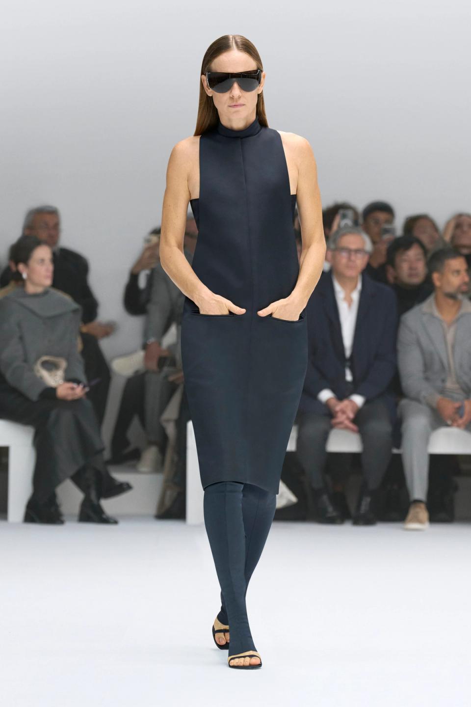 Elegant black sleeveless dress with high neck, showcased by Courrèges on the runway.