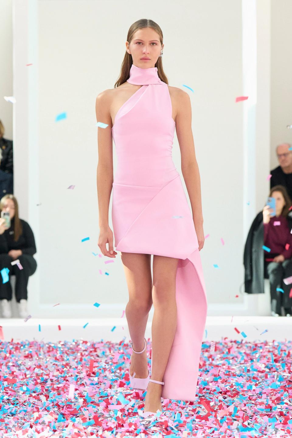 Elegant pink dress by Courrèges showcased on runway with confetti, perfect for fashion lovers.