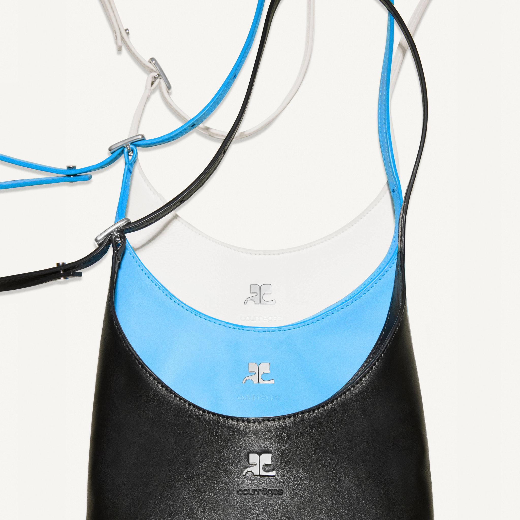 Elegant display of Courrèges handbags in blue, black, and white with minimalist style.
