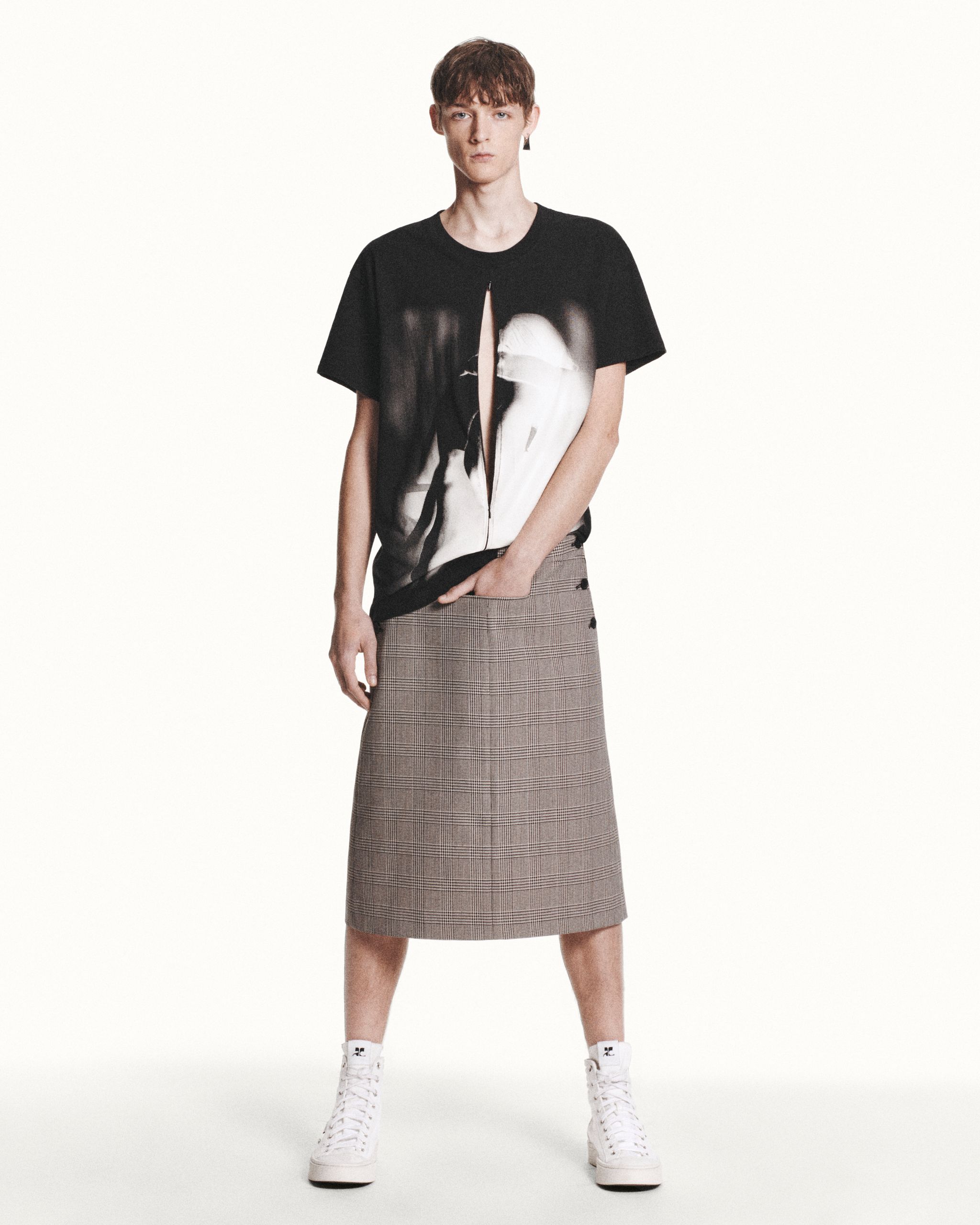 Fashion-forward model wearing Courrèges casual black graphic t-shirt with plaid skirt.