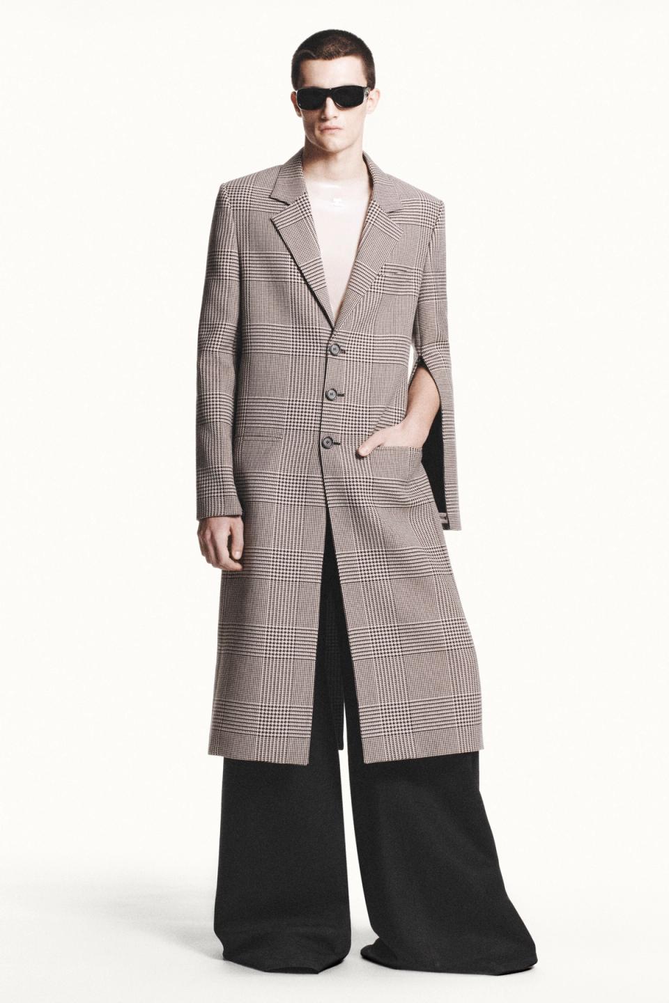 Elegant model in checked coat and wide trousers showcasing Courrèges fashion for online shopping.