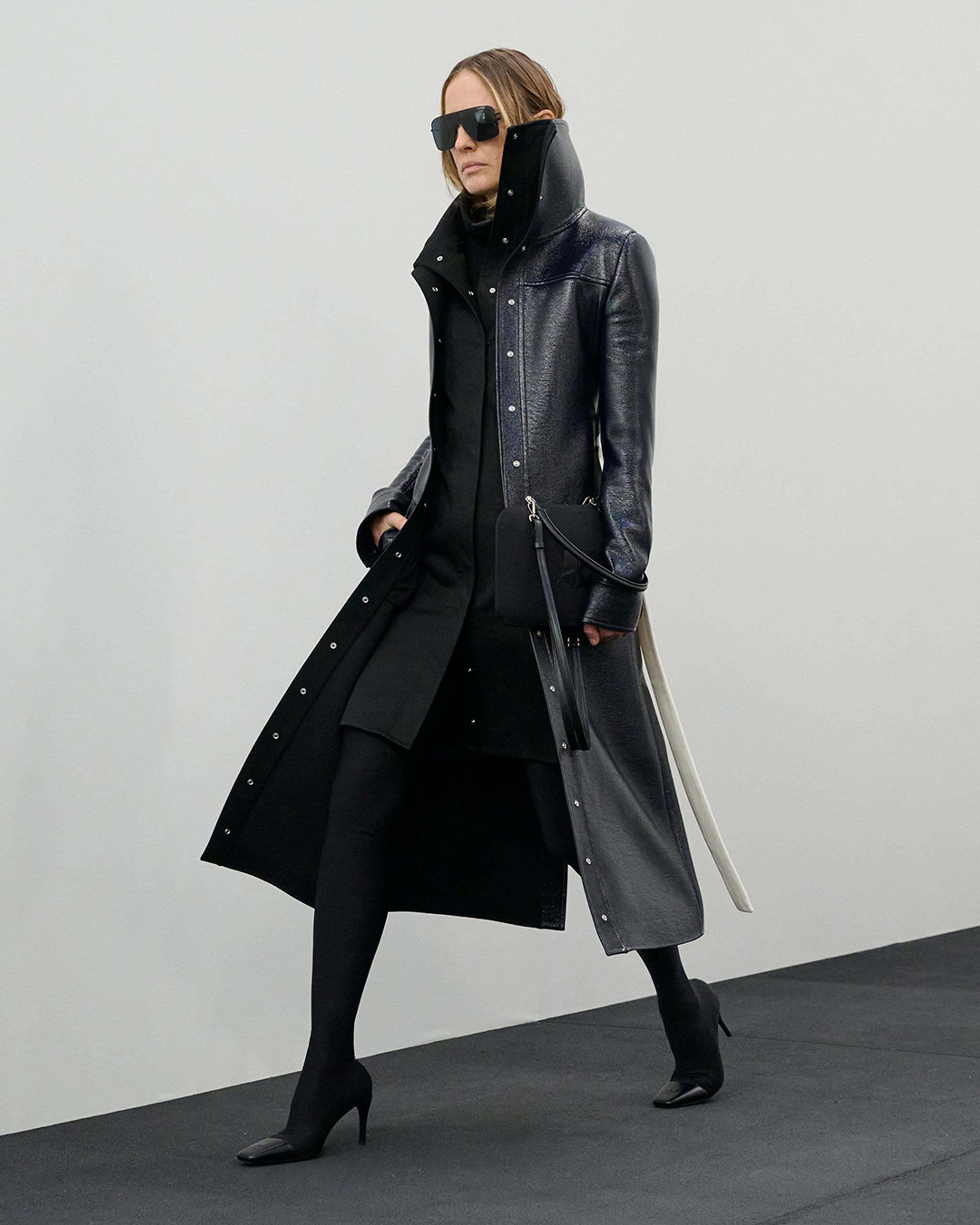 Elegant model in black leather coat and sunglasses, showcasing Courrèges fashion for an ecommerce site.
