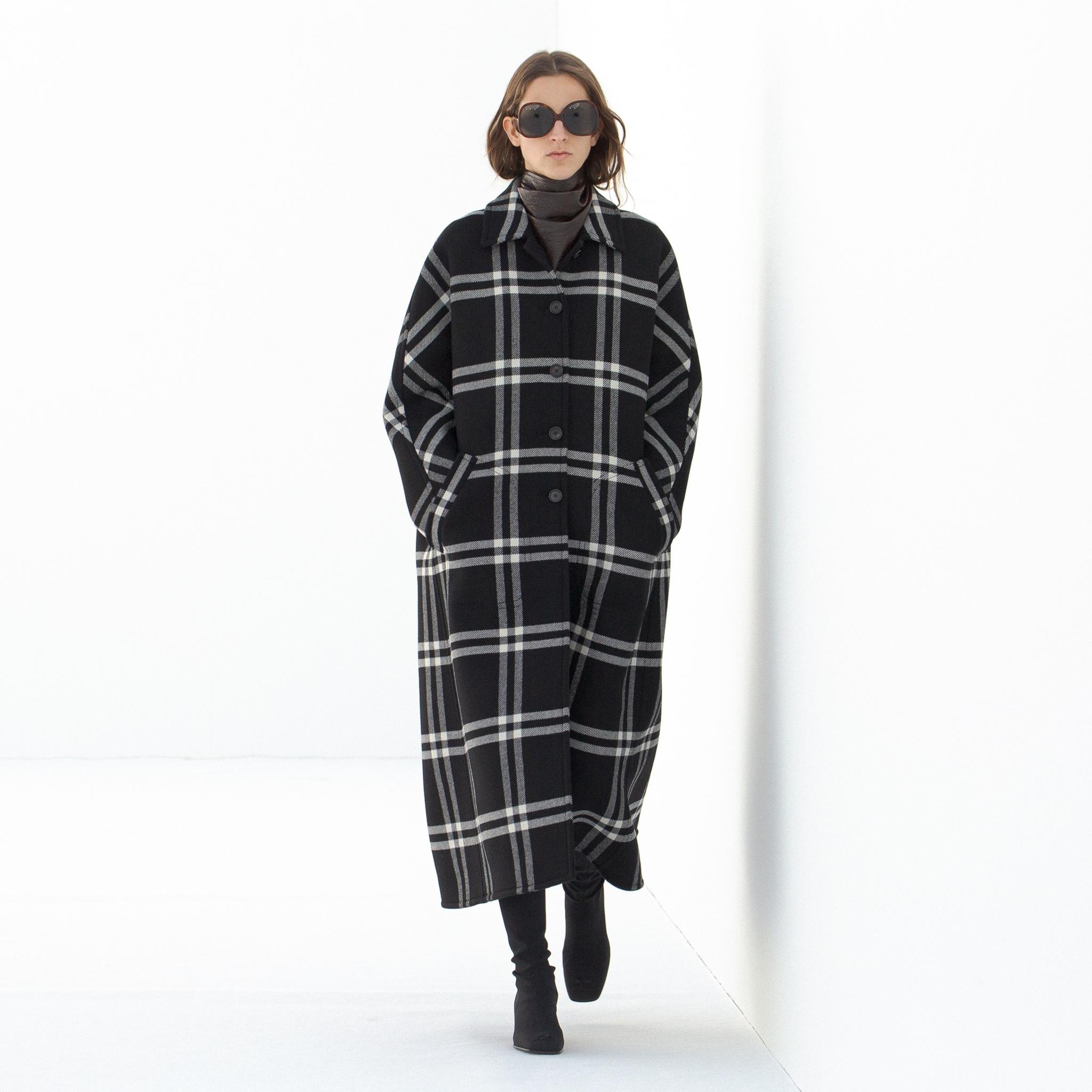 Manteau à carreaux noir et blanc élégant de Courrèges sur un mannequin de défilé, parfait pour les amateurs de mode.