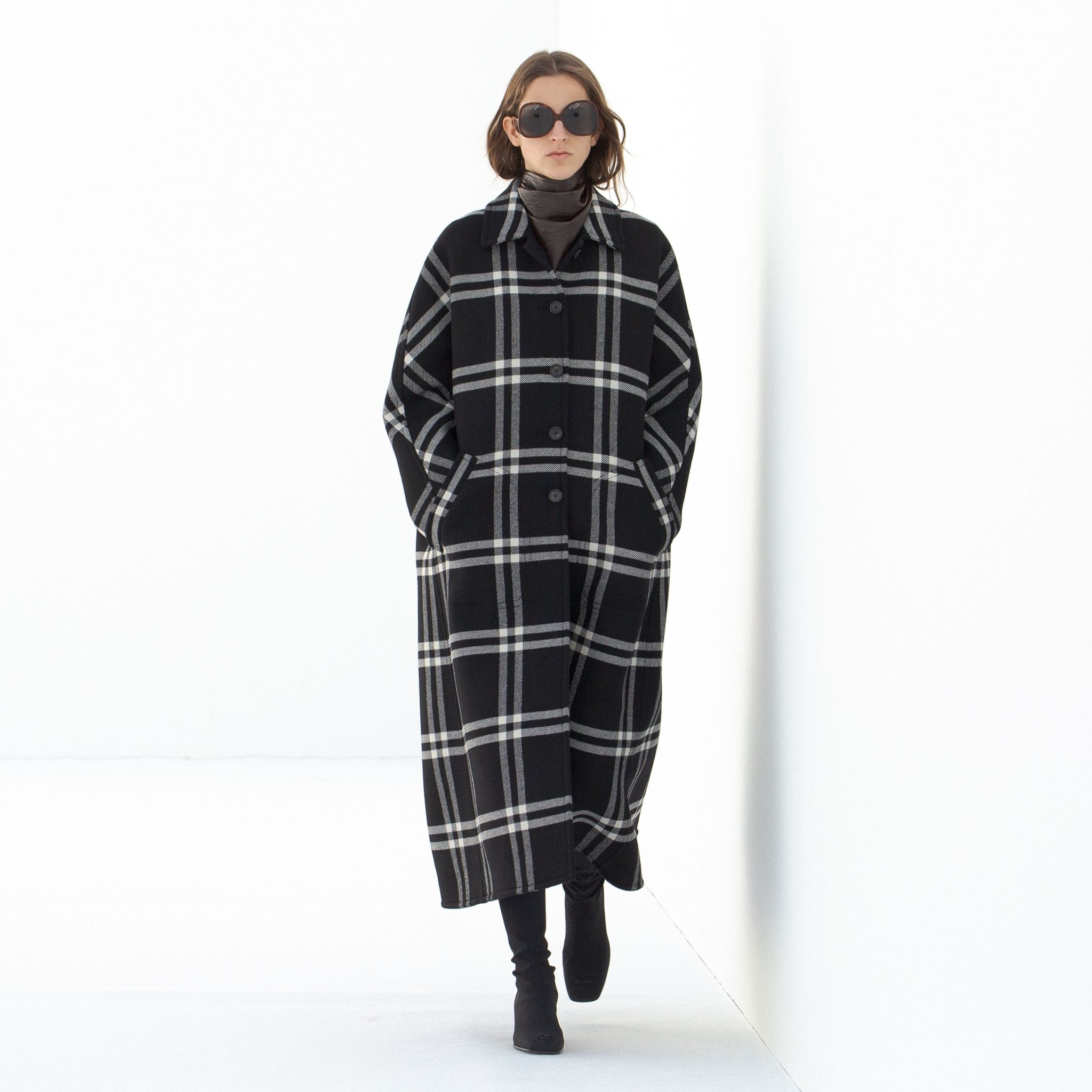 Elegant black and white plaid coat from Courrèges on a runway model, perfect for fashion lovers.