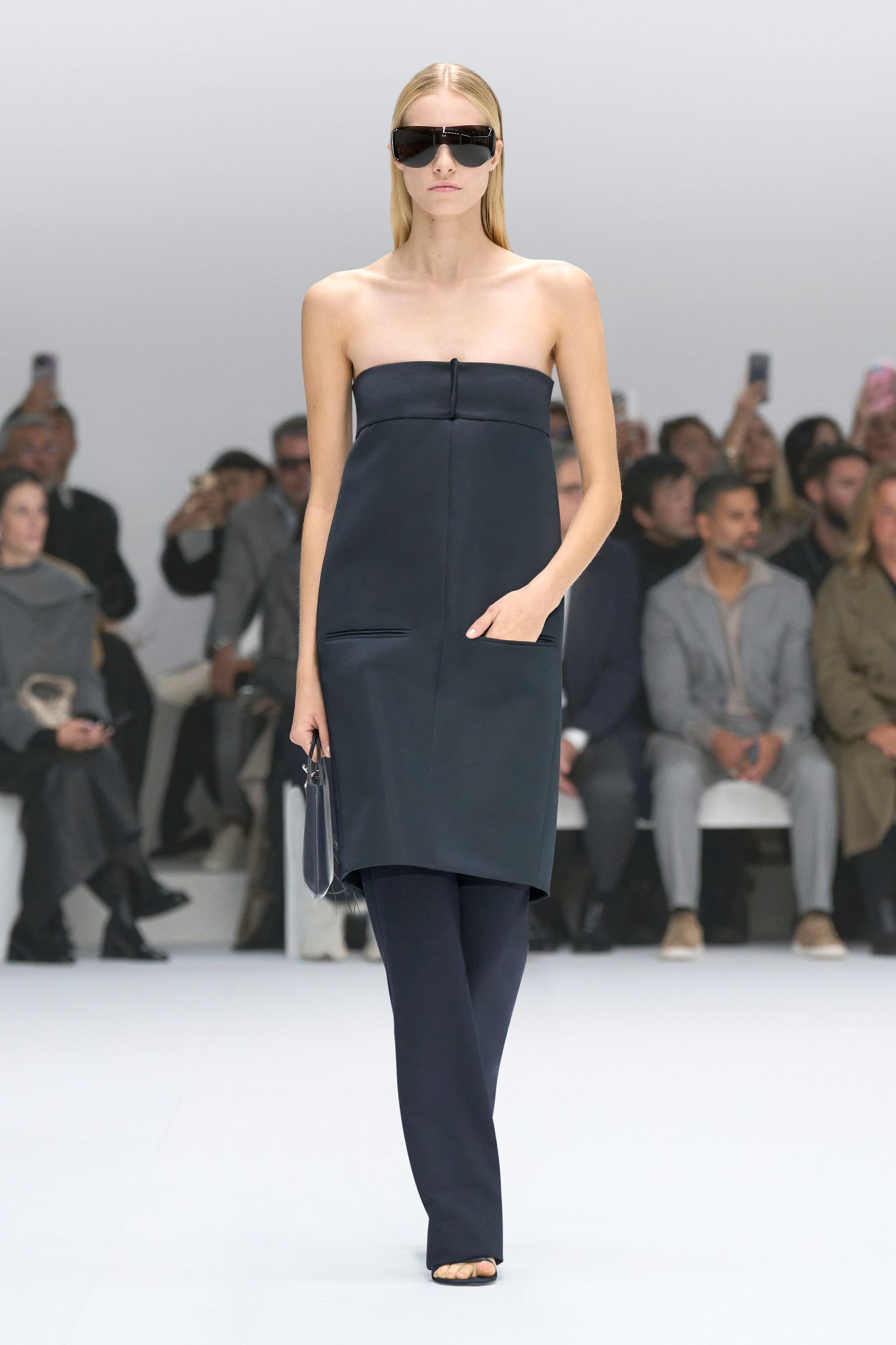 Elegant black strapless dress with a sleek design, showcased on a runway for Courrèges.