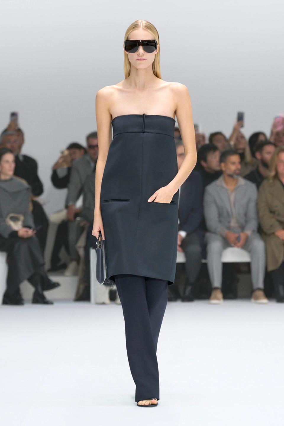 Elegant black strapless dress with a sleek design, showcased on a runway for Courrèges.