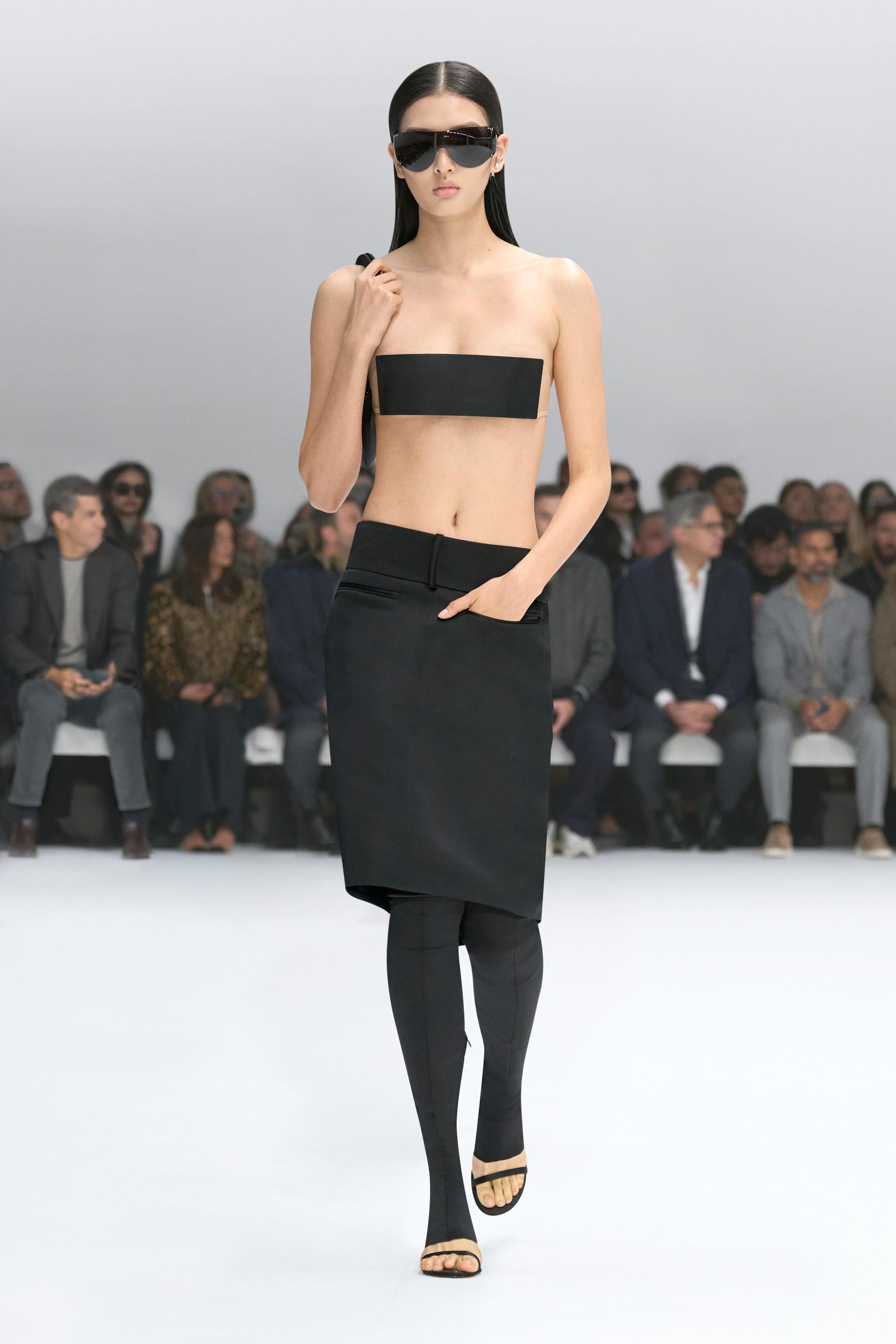 Elegant model in black Courrèges fashion at a runway show, showcasing modern style.