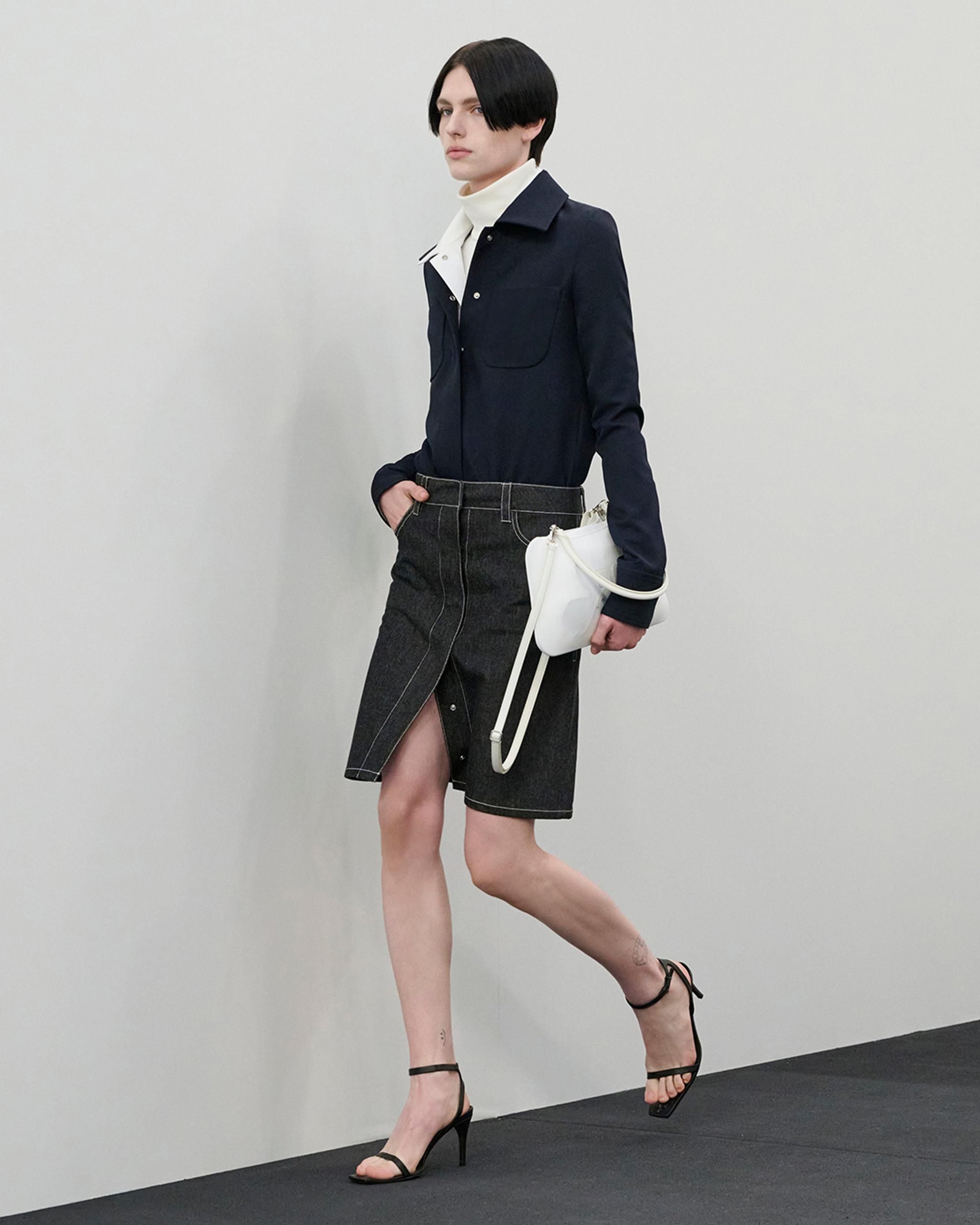 Elegant Courrèges fashion ensemble featuring a navy jacket, grey skirt, and stylish heels.
