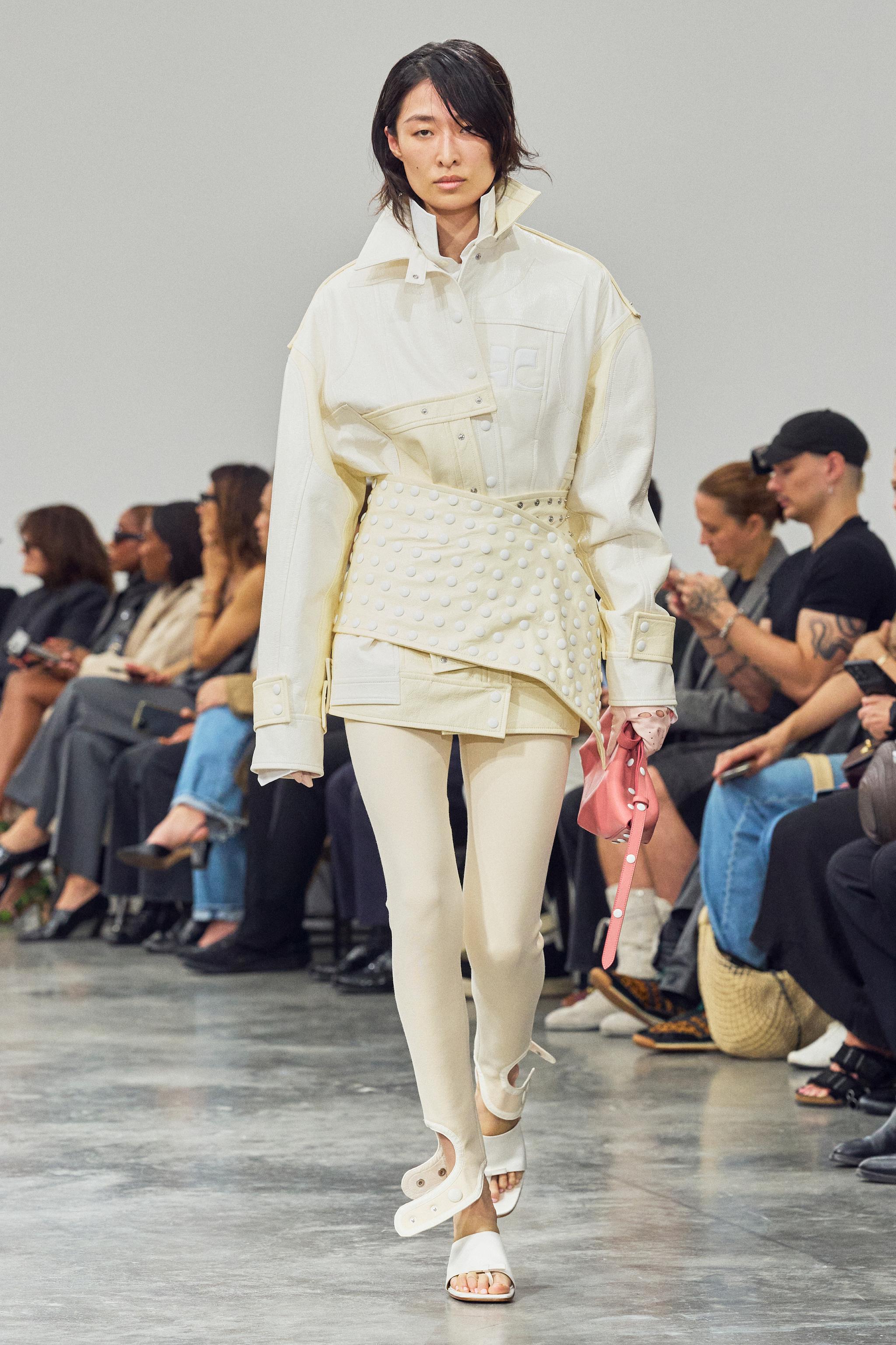 Elegant white fashion runway look with Courrèges branding, featuring a stylish jacket and skirt.