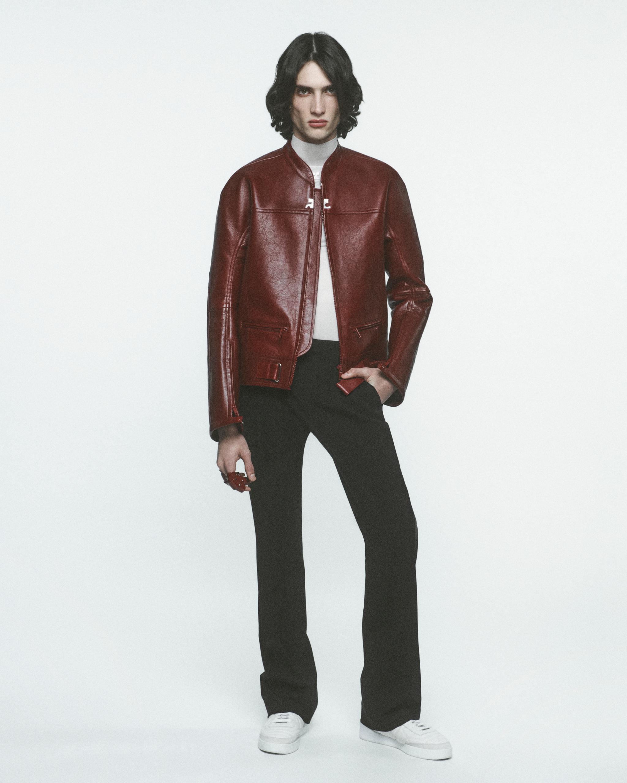 Elegant model wearing a red leather jacket, black pants, and white sneakers for Courrèges.