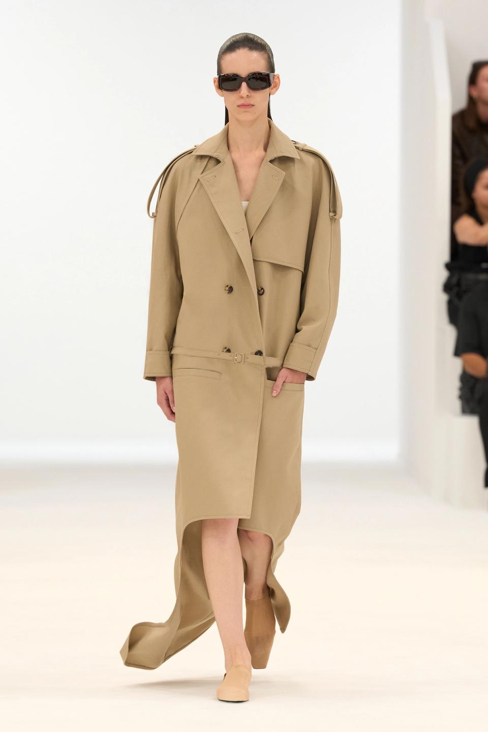 Elegant beige trench coat and matching skirt showcase Courrèges' modern fashion on runway.