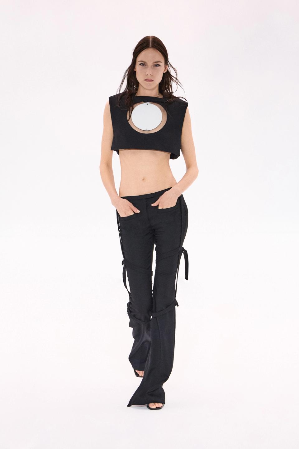 Elegant black designer crop top with a circular mirror cutout, showcased by model for Courrèges.