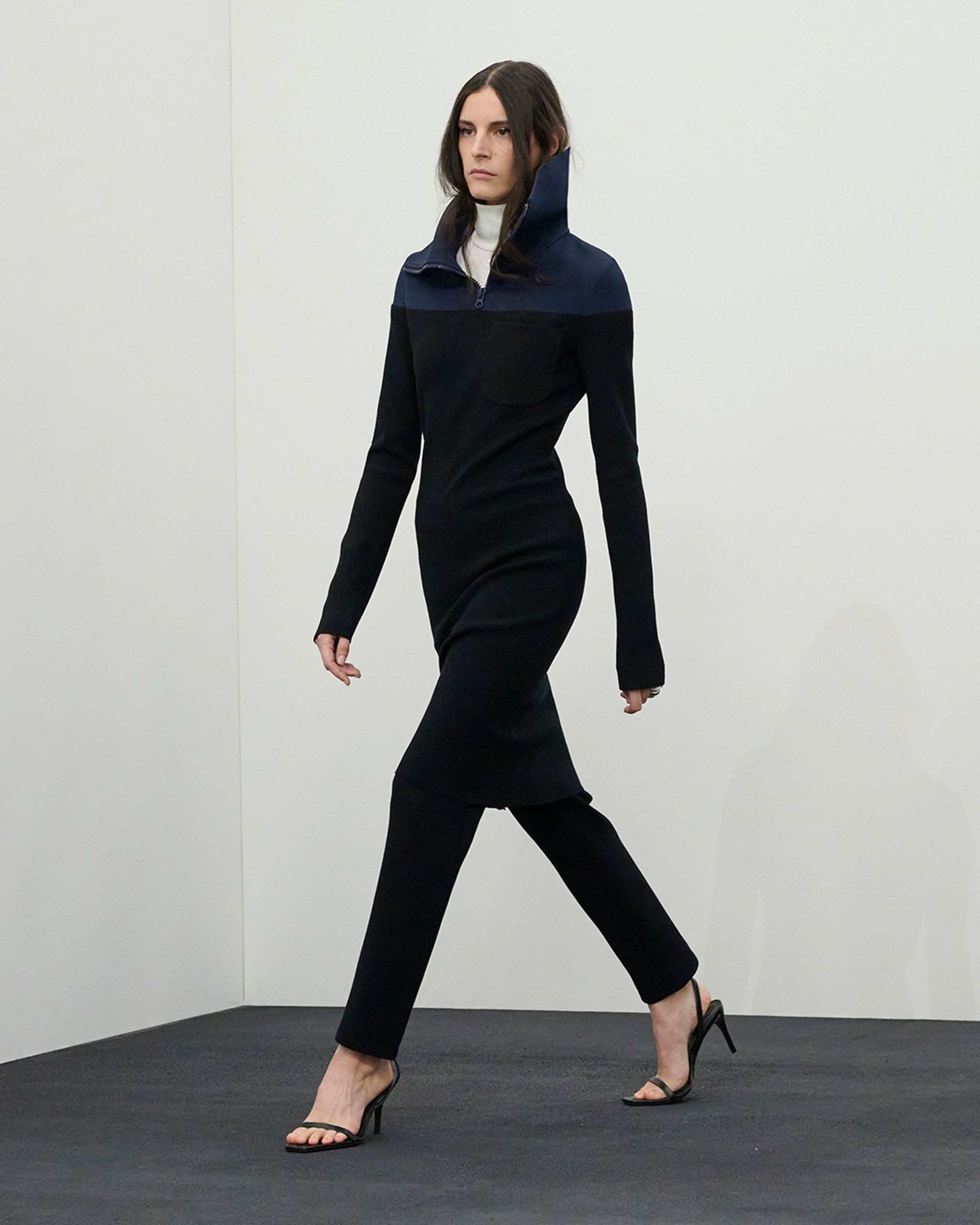 Robe noire élégante avec col haut et fermeture éclair, signée Courrèges, idéale pour un style sophistiqué.