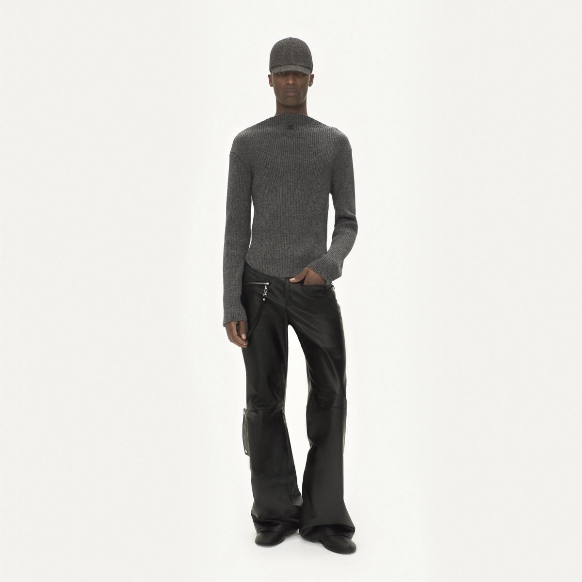 Elegant model in grey knit sweater and black leather pants on a white background for Courrèges.