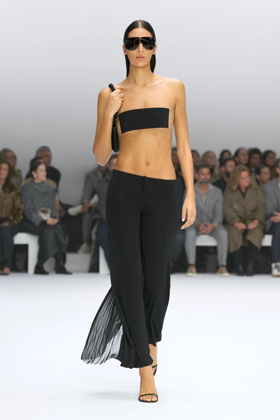 Elegant black fashion ensemble by Courrèges, featuring a strapless top, flowy pants, and bold accessories.