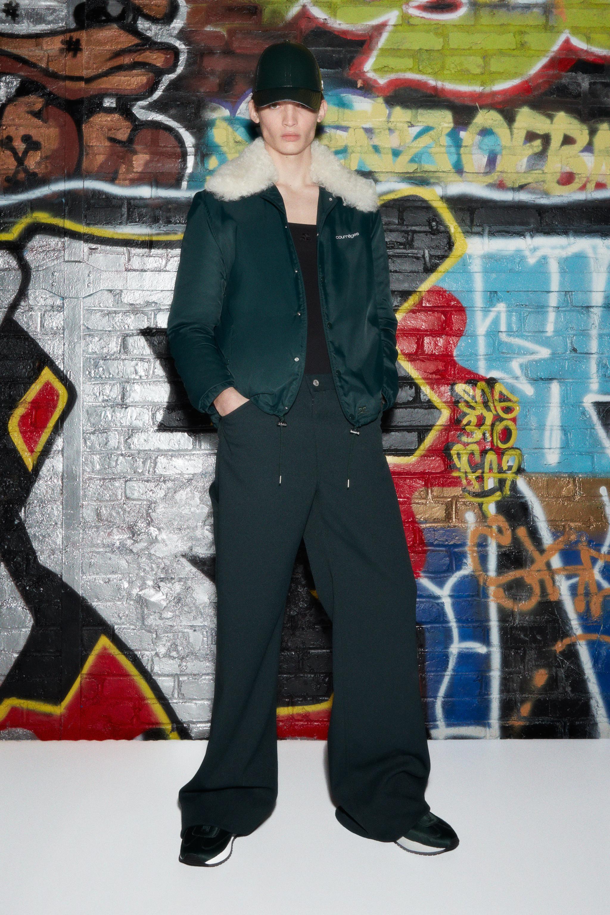 Elegant Courrèges fashion jacket with faux shearling collar, showcased on a model against graffiti.