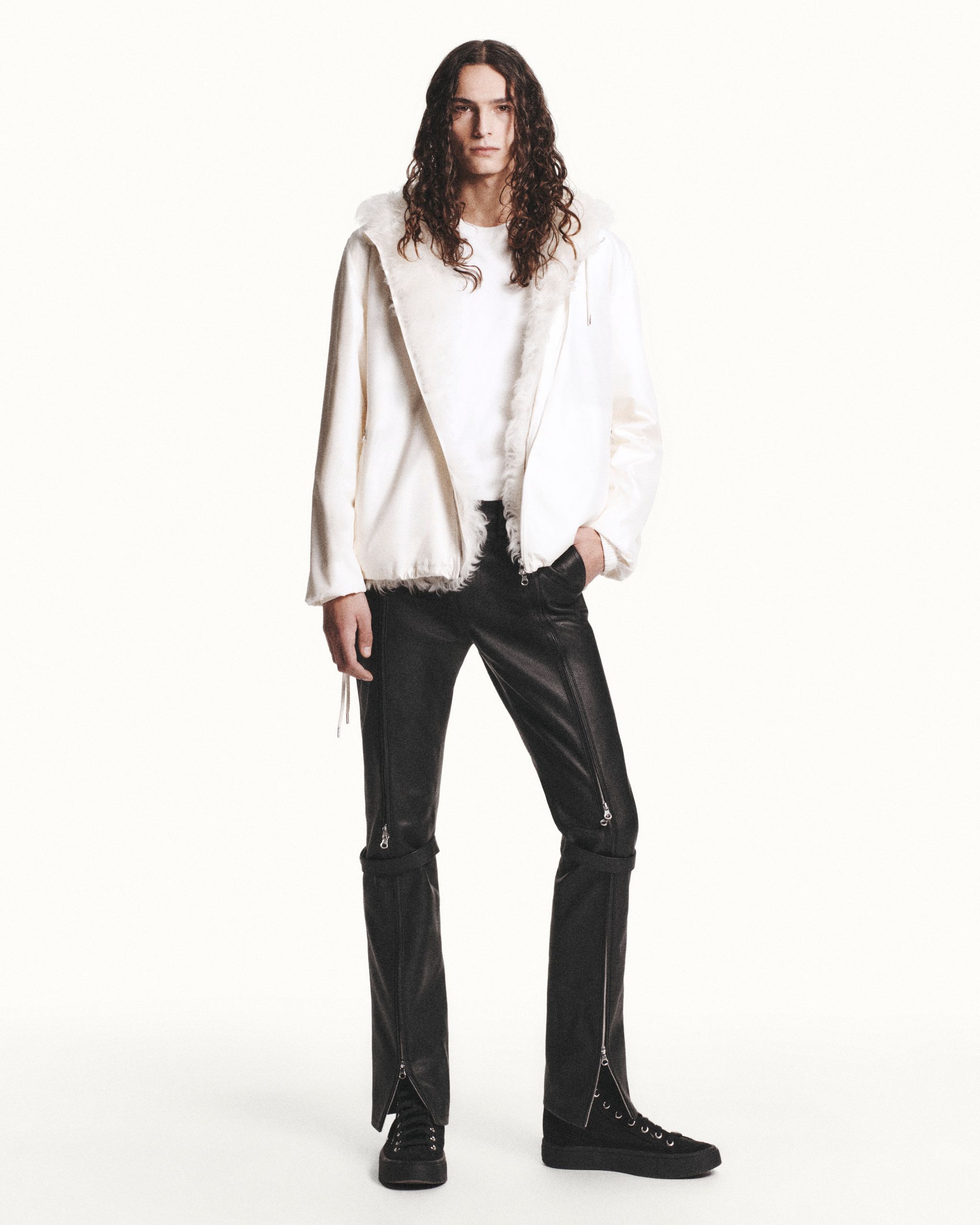 Elegant Courrèges fashion showcase featuring a model in a stylish white jacket, black leather pants, and sneakers.