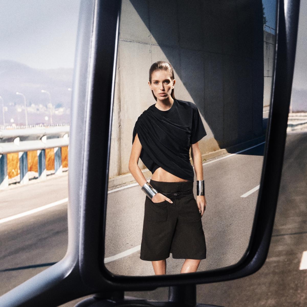 Elegant Courrèges fashion showcased through a model's stylish black ensemble on a city street.