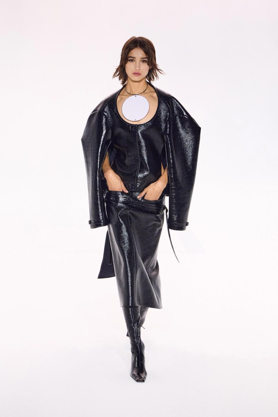 Elegant black shiny leather ensemble with modern style, showcased on a runway for Courrèges.