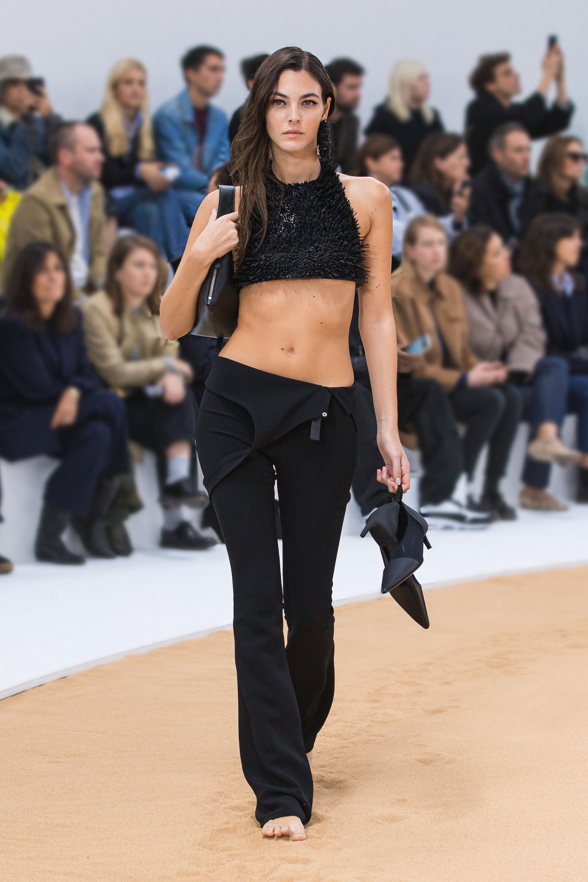 Elegant black crop top and black pants by Courrèges showcased on a runway with audience.