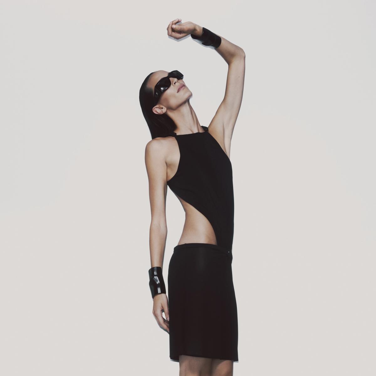 Elegant Courrèges fashion model wearing sunglasses, black cutout dress, and accessories.